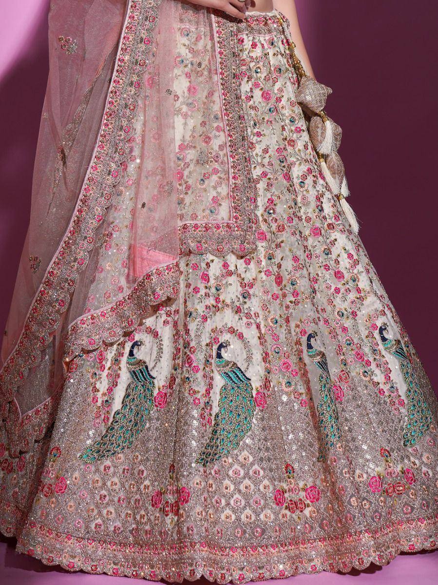 Elegant ivory lehenga choli with peacock embroidery and pink floral motifs, perfect for Indian weddings.