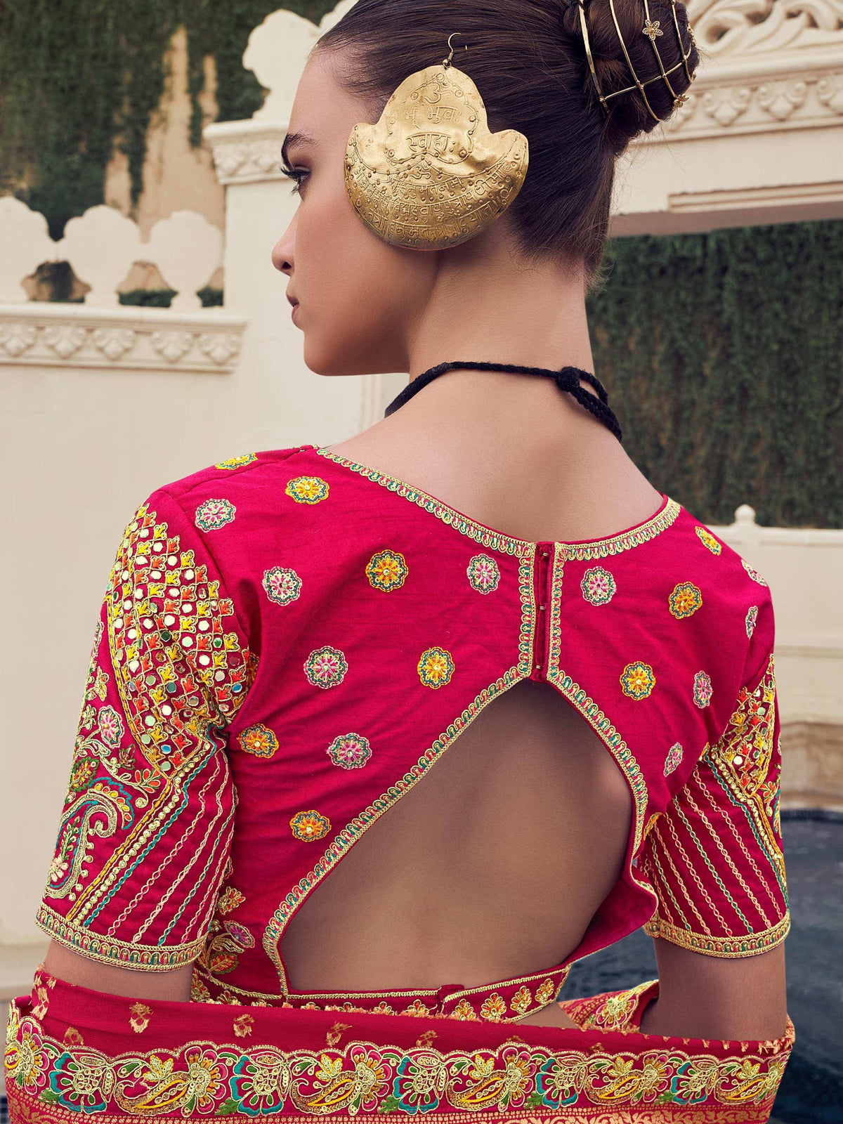 Red embroidered lehenga choli with back cutout, mirror work, and gold temple jewelry for Indian ethnic wear
