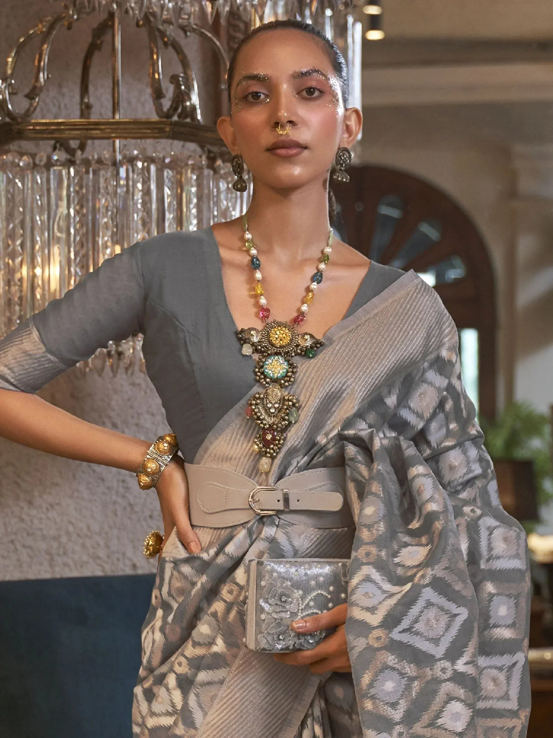 Stylish grey ikat saree with designer blouse, statement jewelry, and belt for ethnic wear