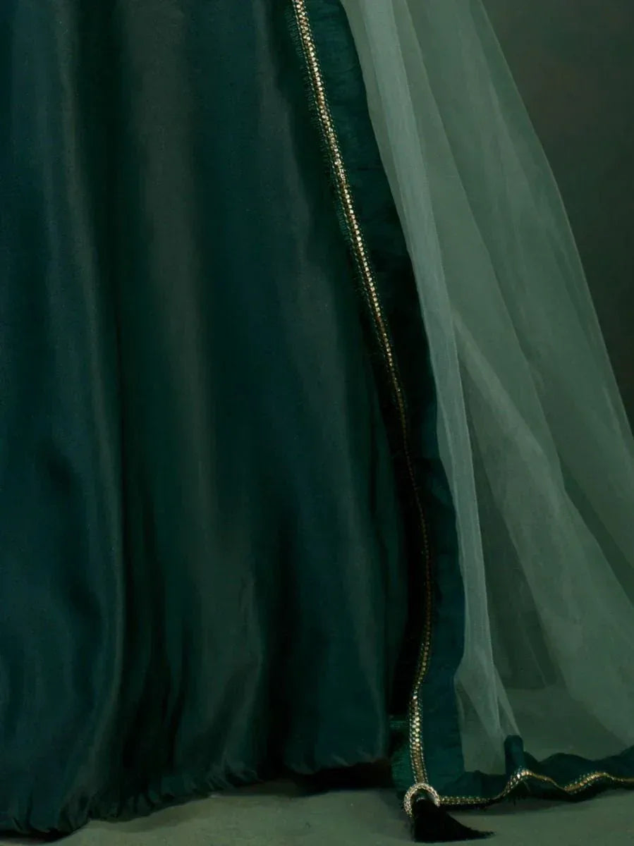 Emerald green ethnic gown with gold trim and sheer overlay, perfect for Indian weddings and festive occasions.