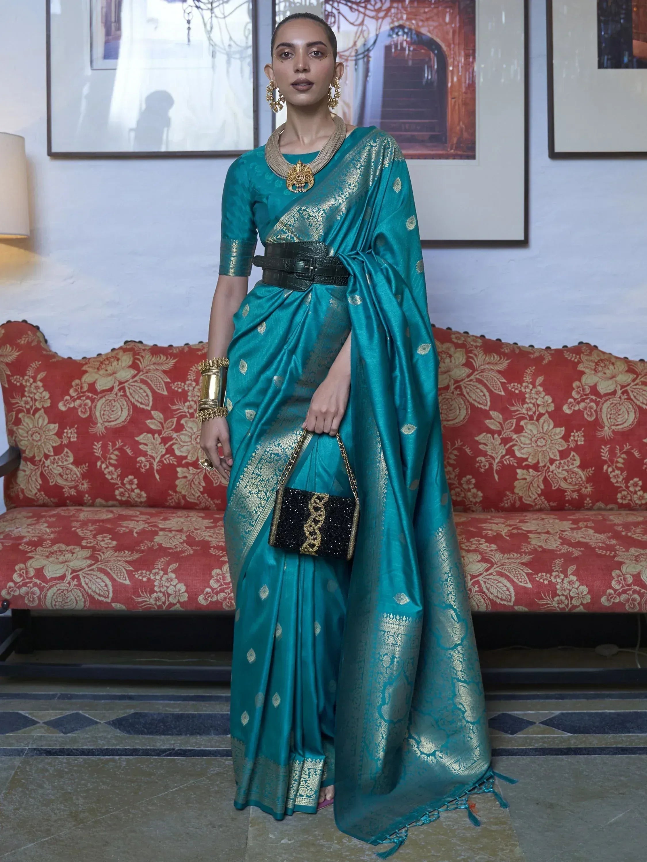 Teal silk saree with gold zari, black belt, and statement jewelry for ethnic wear