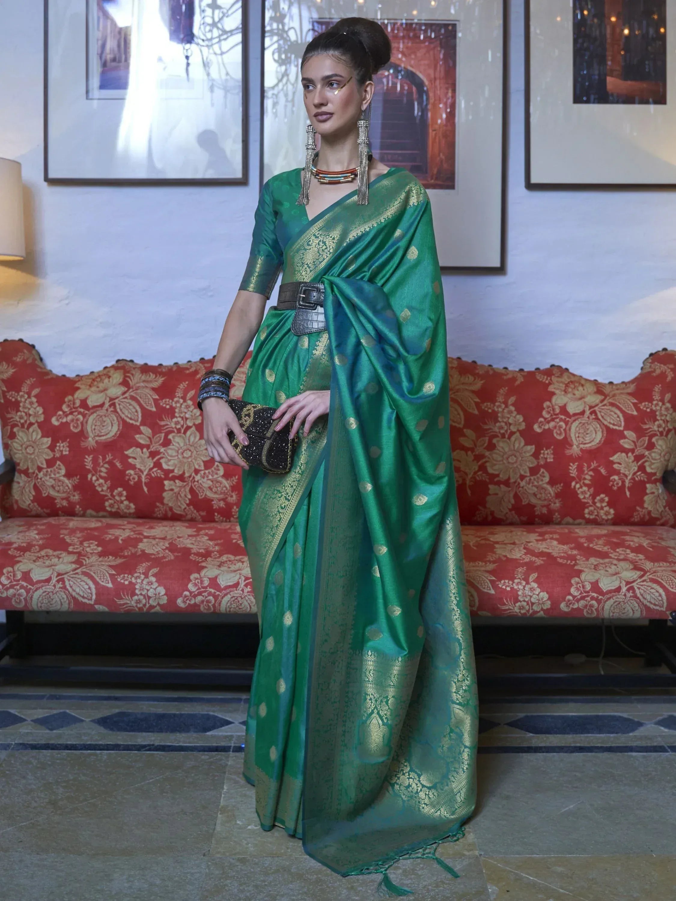Emerald green silk saree with gold zari work, styled with belt and statement jewelry for ethnic wear