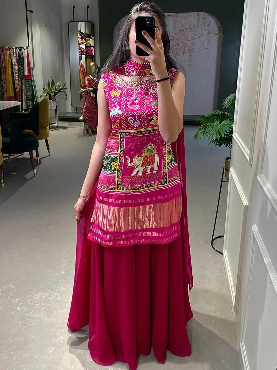 Woman wearing pink ethnic lehenga with elephant print and mirror work in modern boutique.