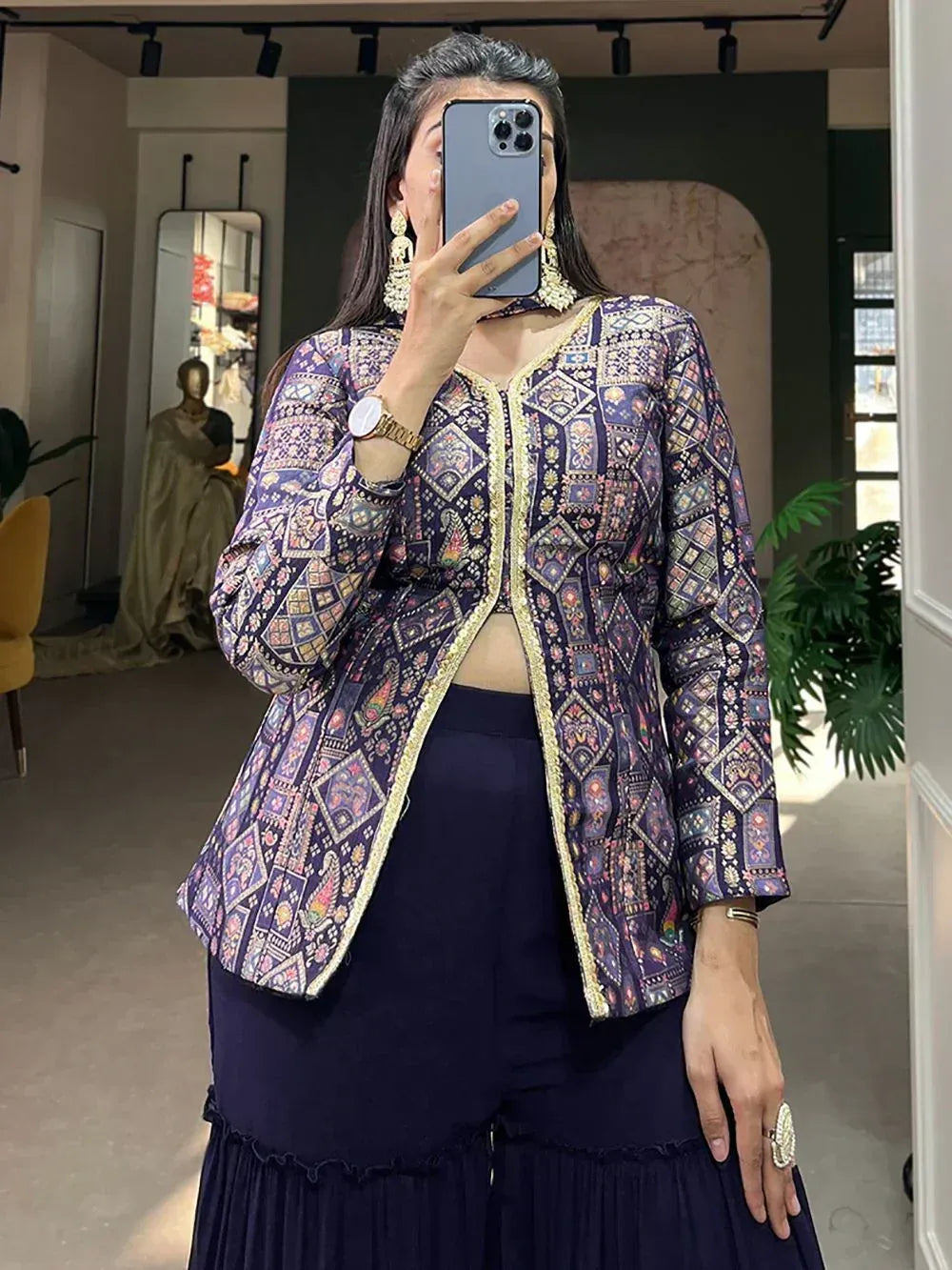 Woman wearing purple printed ethnic jacket with gold trim, paired with navy palazzo pants, in boutique setting