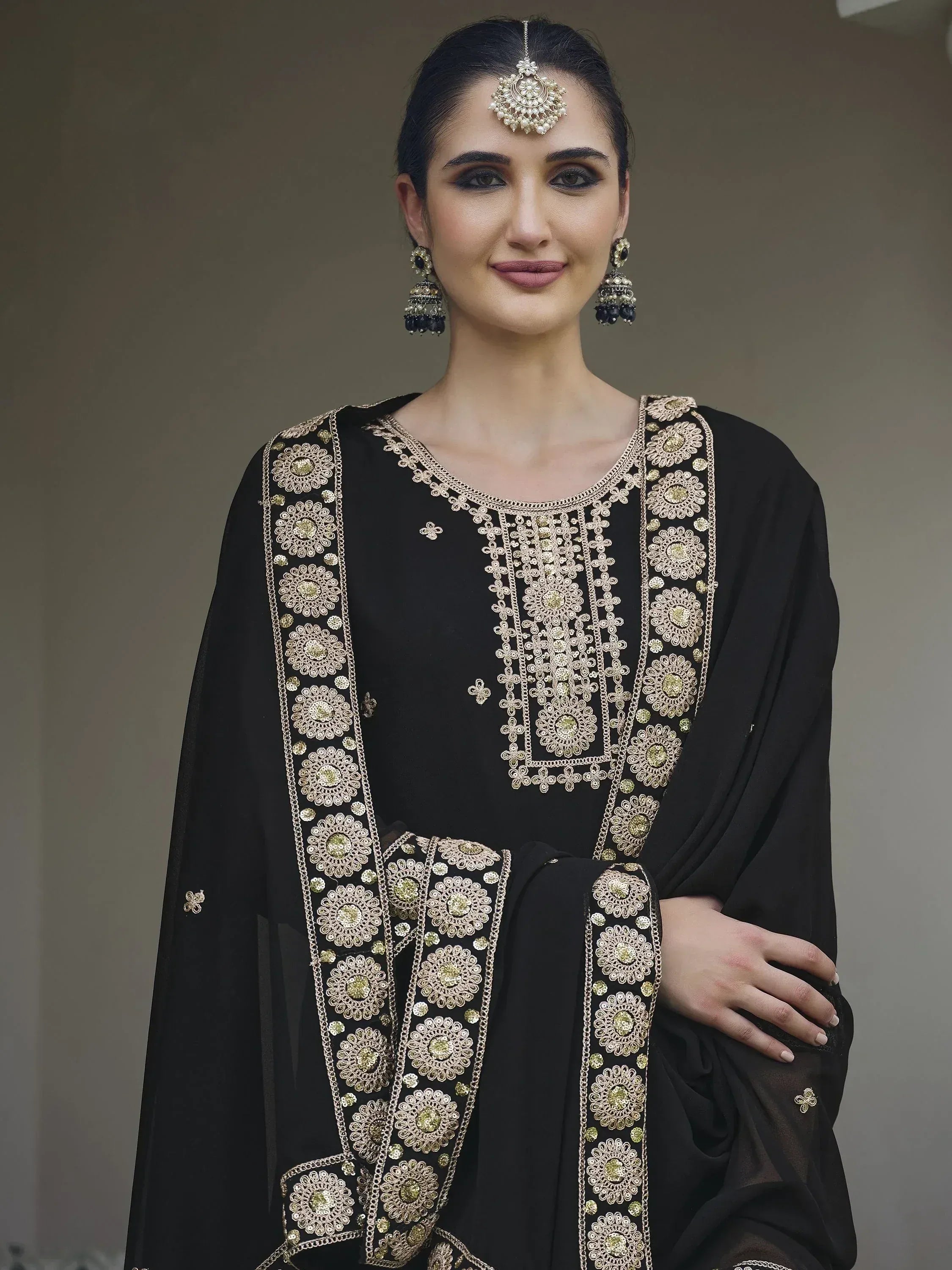 Woman in black embroidered salwar kameez with dupatta and traditional jewelry