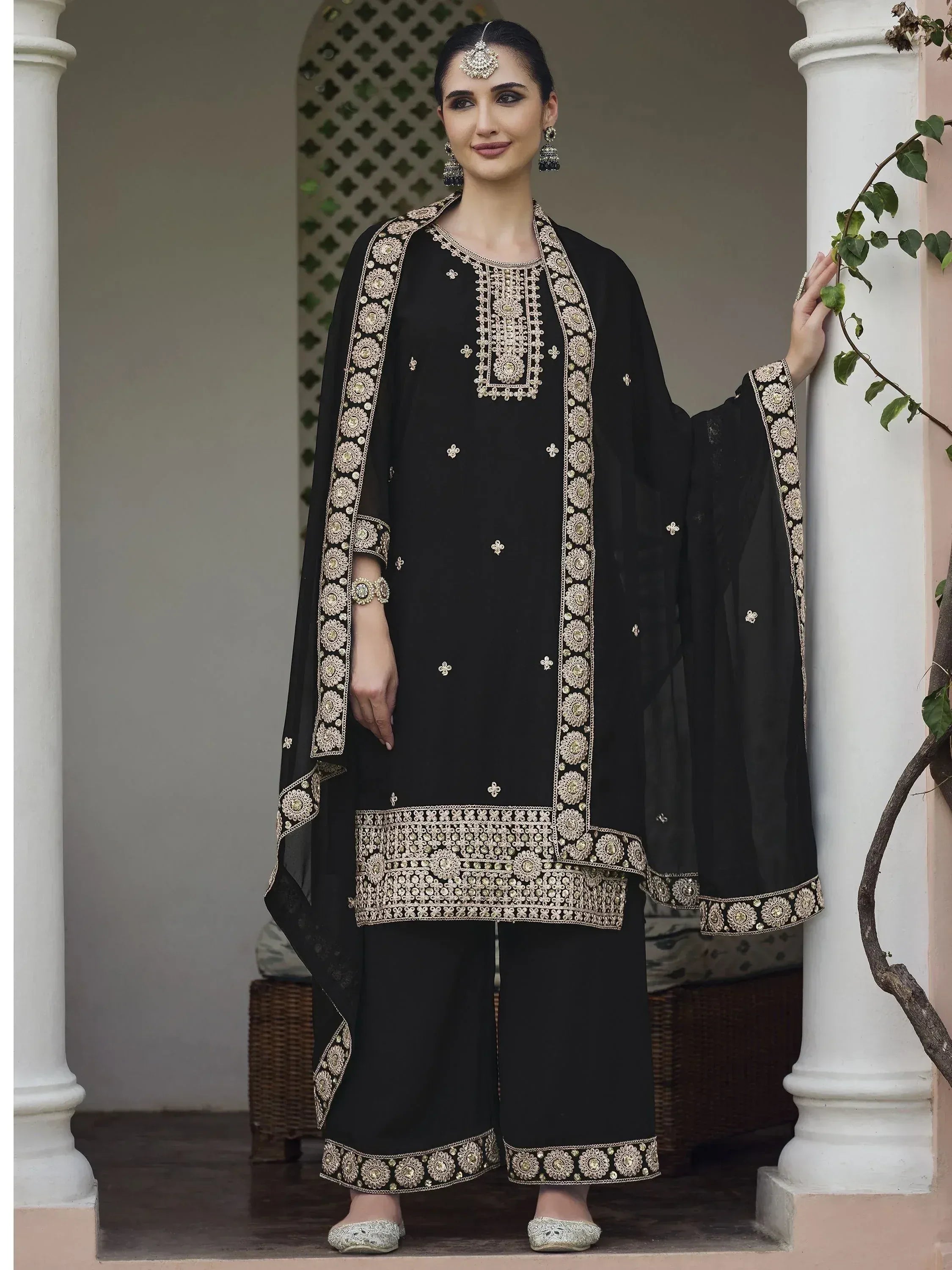 Woman wearing a black embroidered salwar kameez with palazzo pants and matching dupatta