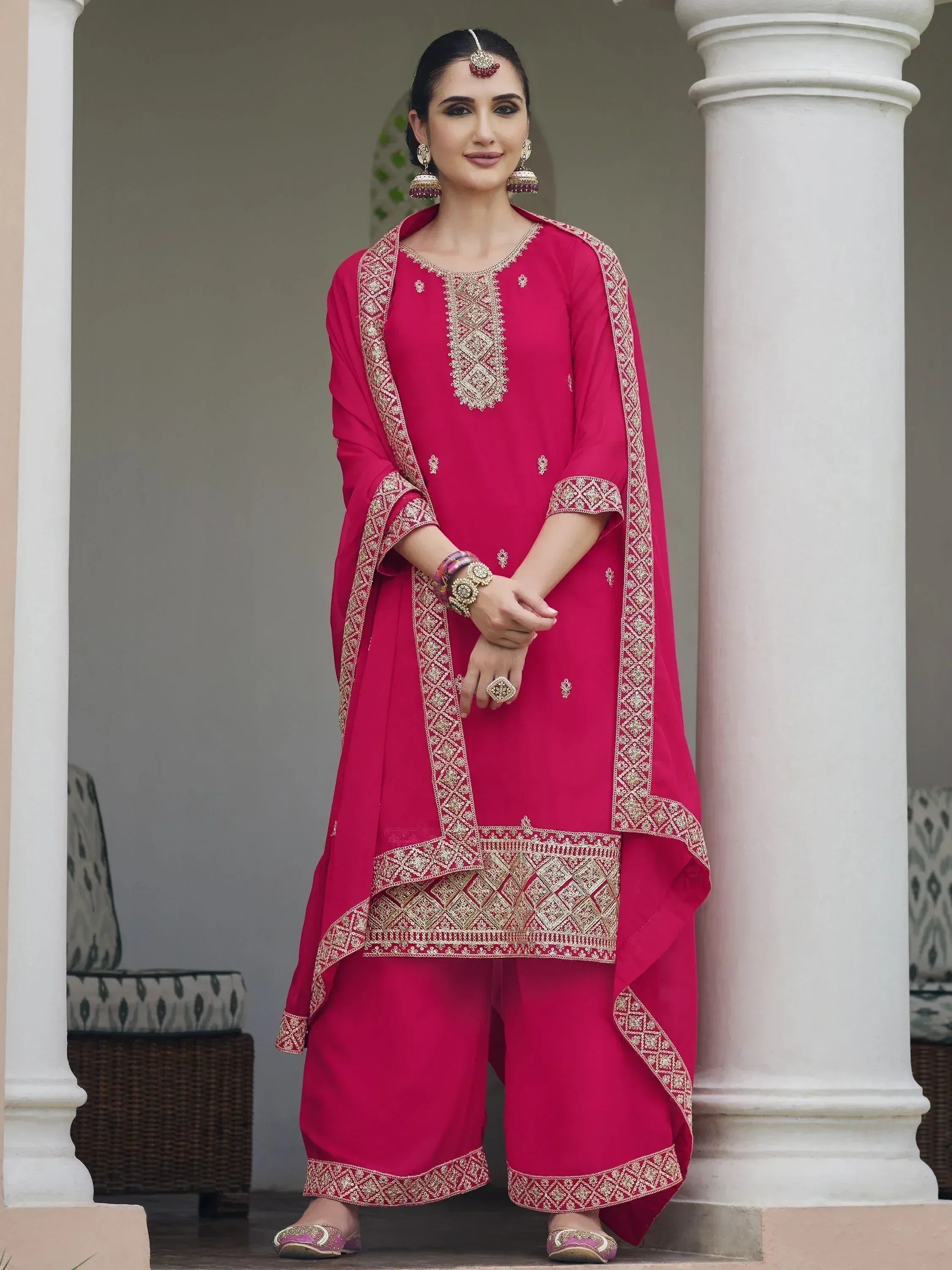 Woman wearing a pink embroidered salwar kameez with dupatta, traditional Indian ethnic wear.