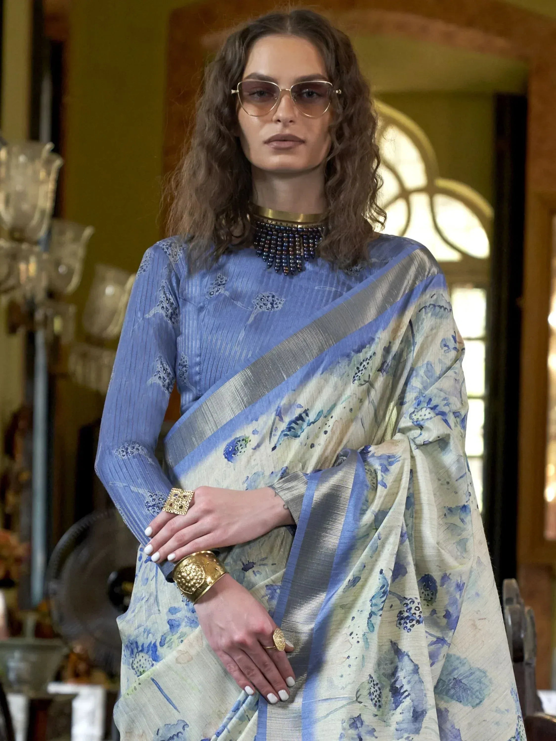 Blue floral printed saree with silver border, styled with gold jewelry for ethnic wear