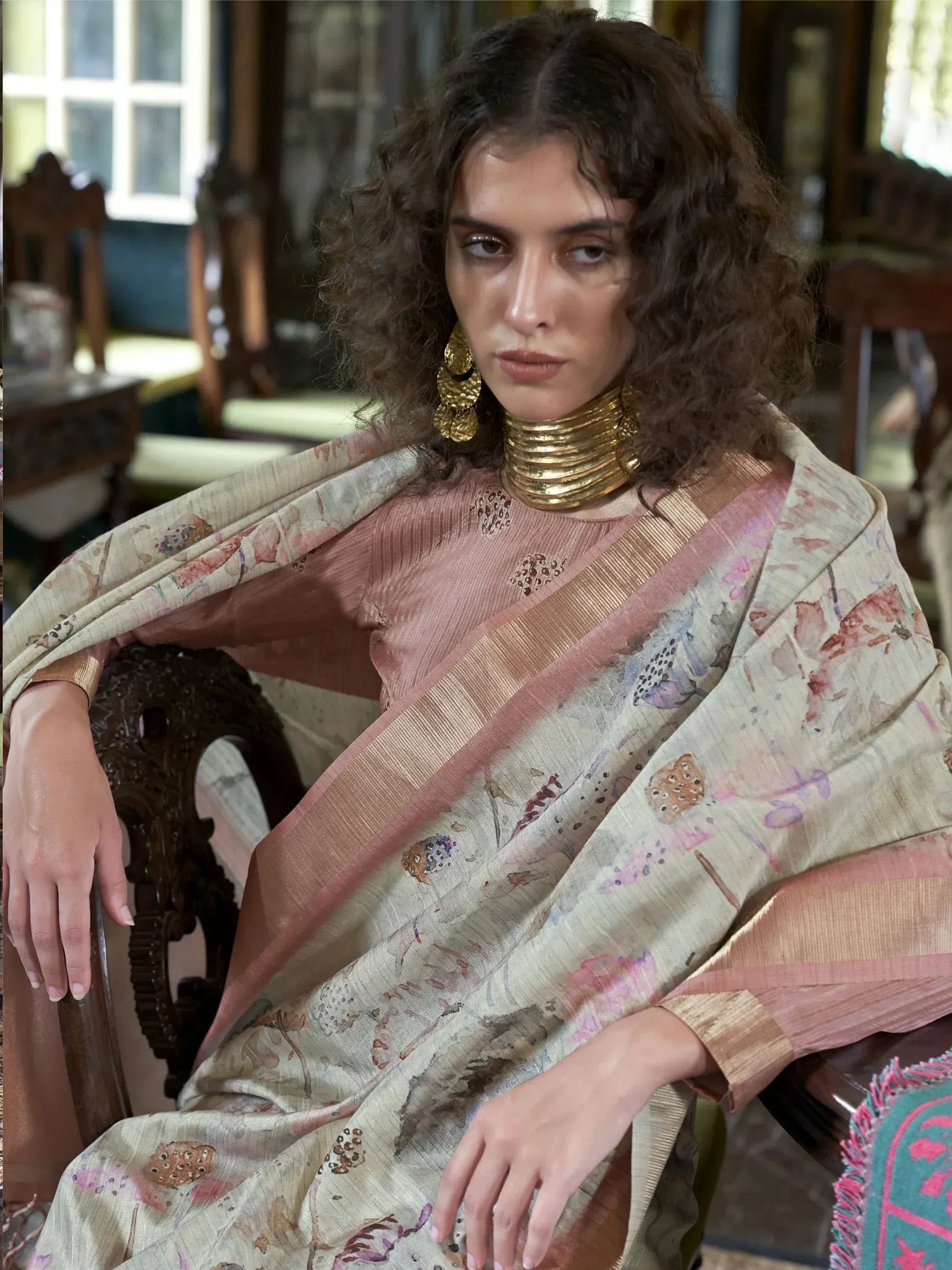 Woman in elegant floral saree with gold jewelry, showcasing Indian ethnic wear for festive occasions.