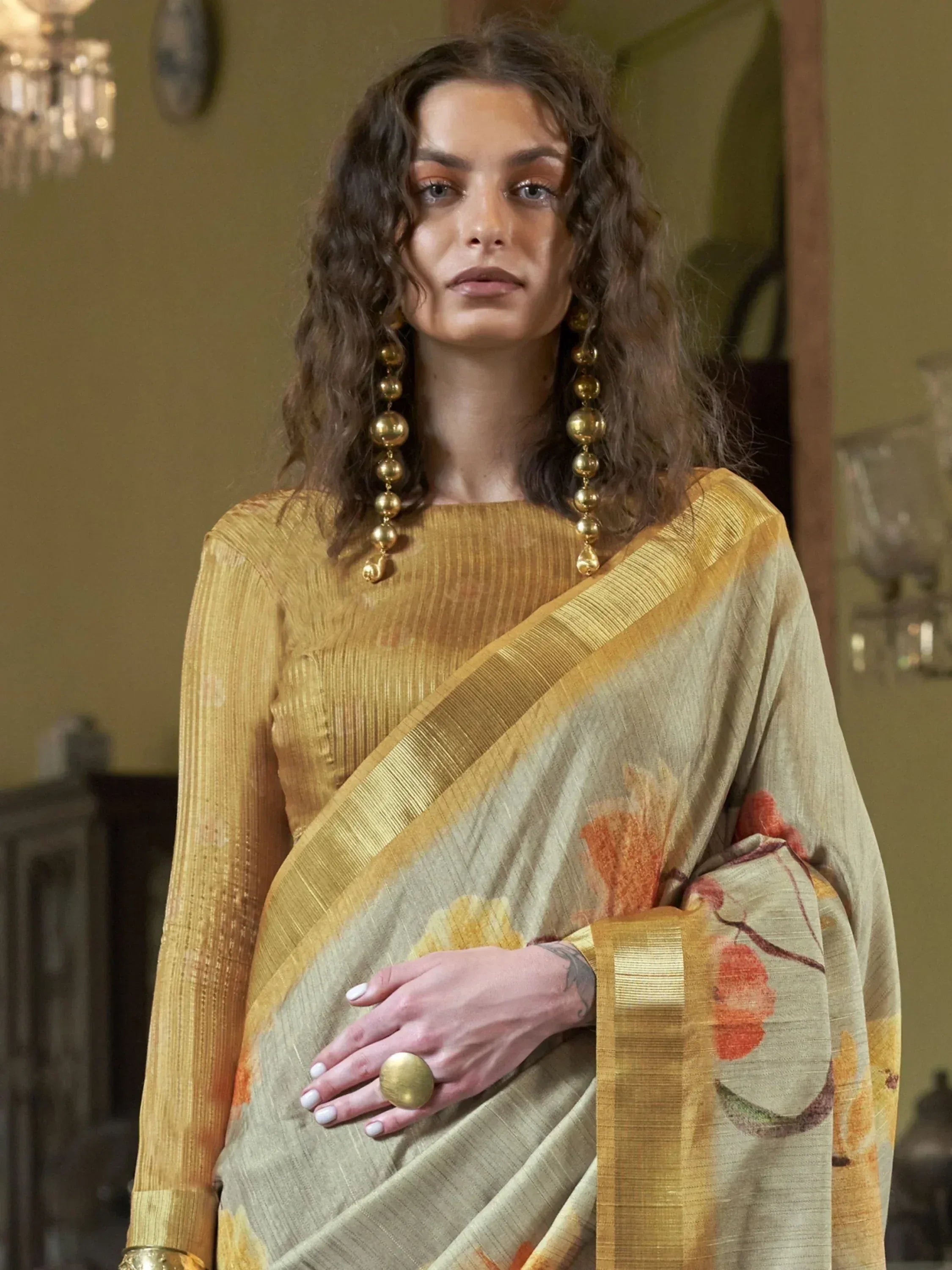 Woman in elegant floral print saree with golden border, styled with matching blouse and statement jewelry