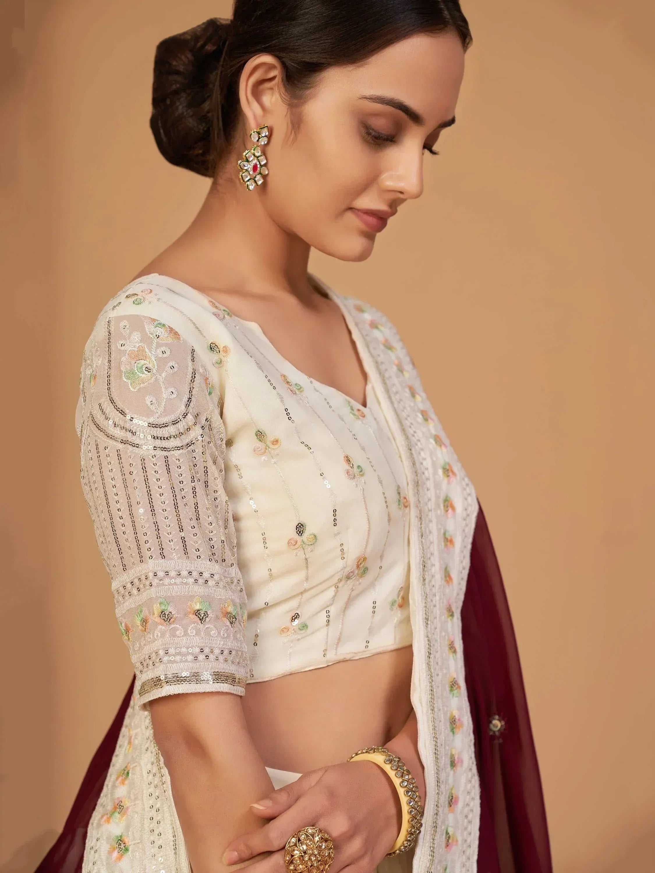 Elegant ivory embroidered blouse with sheer sleeves, floral motifs, and sequins, paired with maroon dupatta for Indian ethnic wear.