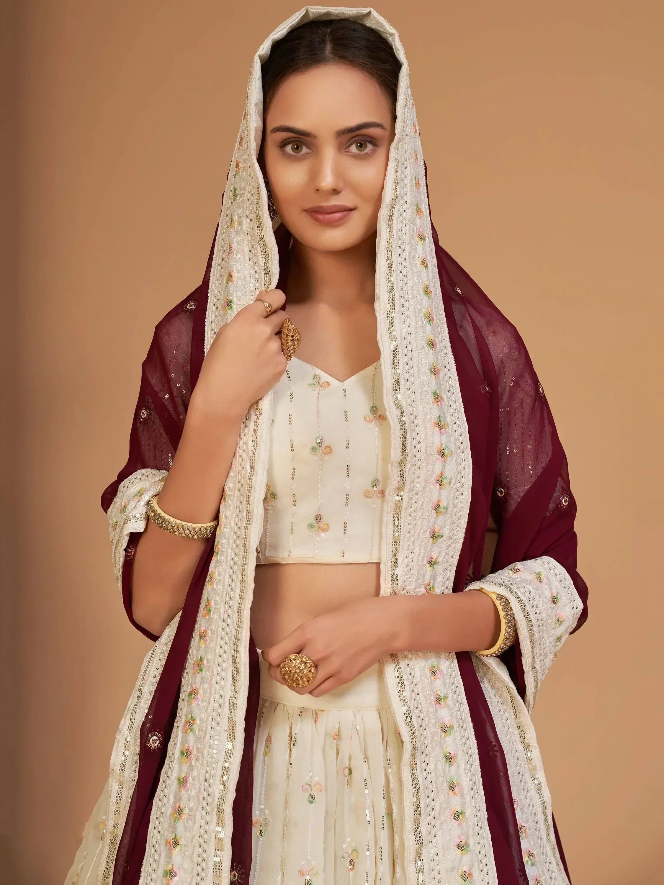 Elegant cream and maroon ethnic lehenga choli with floral embroidery and dupatta, perfect for Indian weddings or festive occasions.