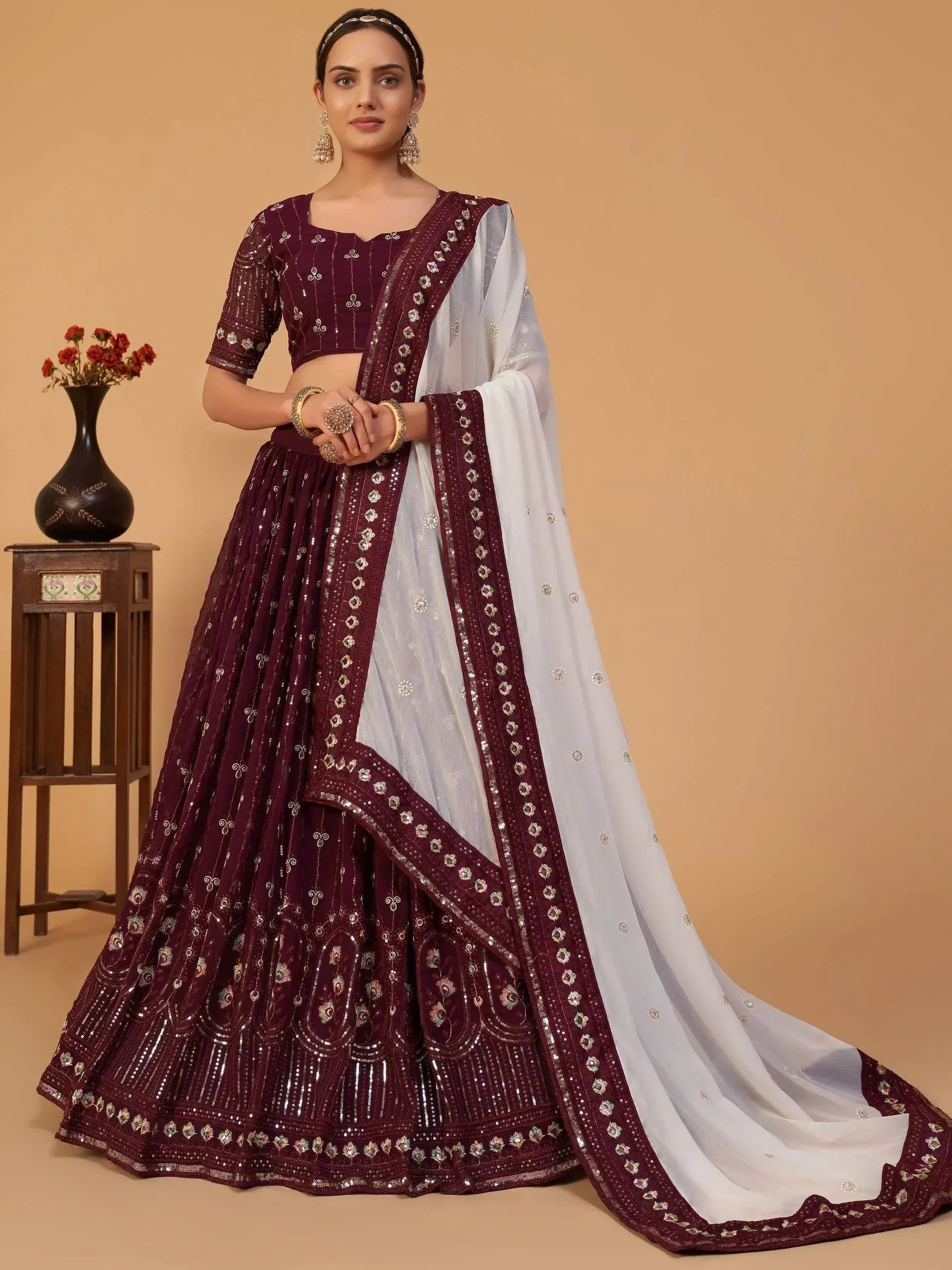 Elegant maroon lehenga choli with white dupatta, featuring intricate embroidery and sequin work for Indian ethnic wear.