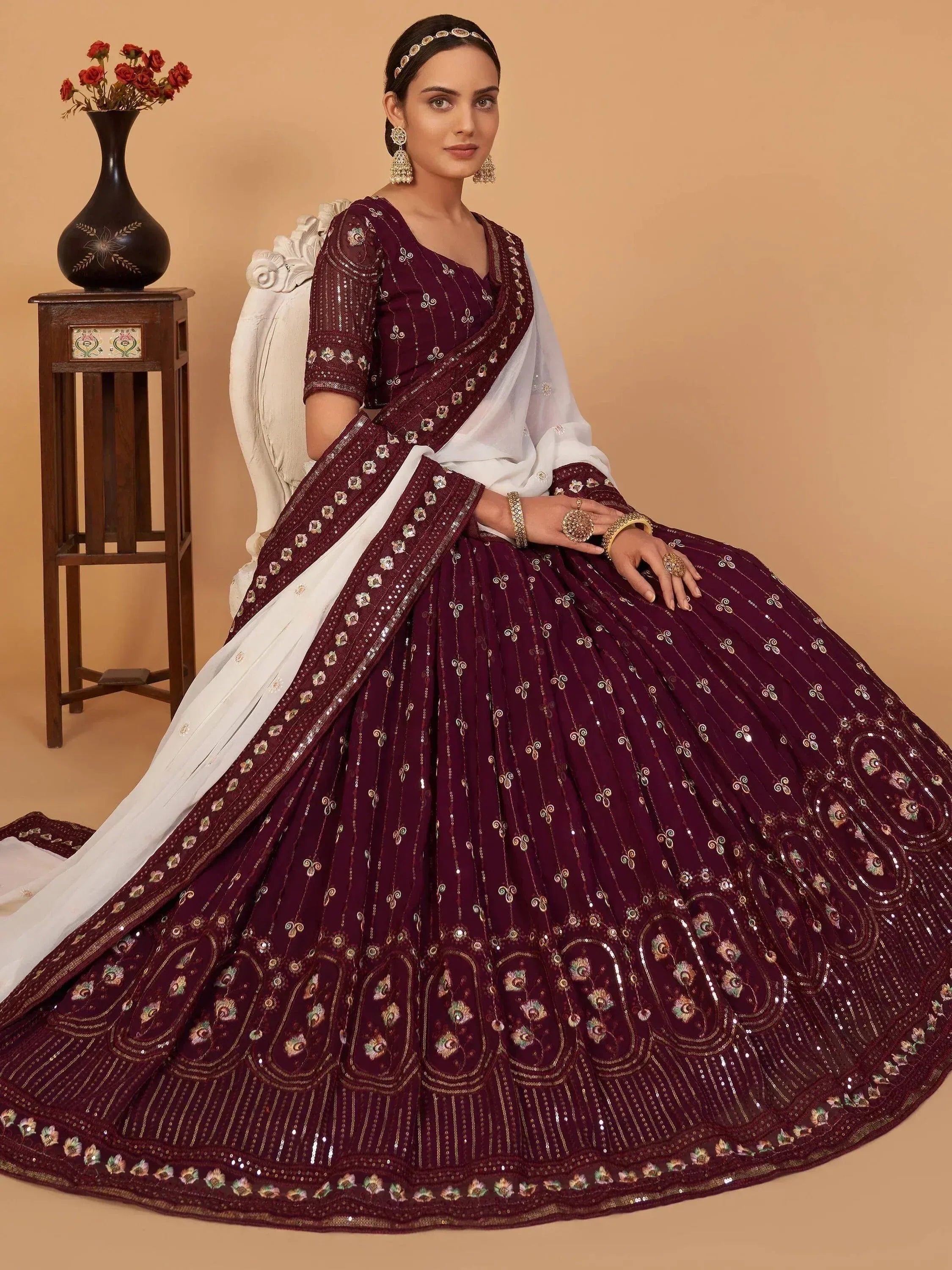 Elegant maroon lehenga choli with gold embroidery and white dupatta, perfect for Indian weddings and festive occasions.