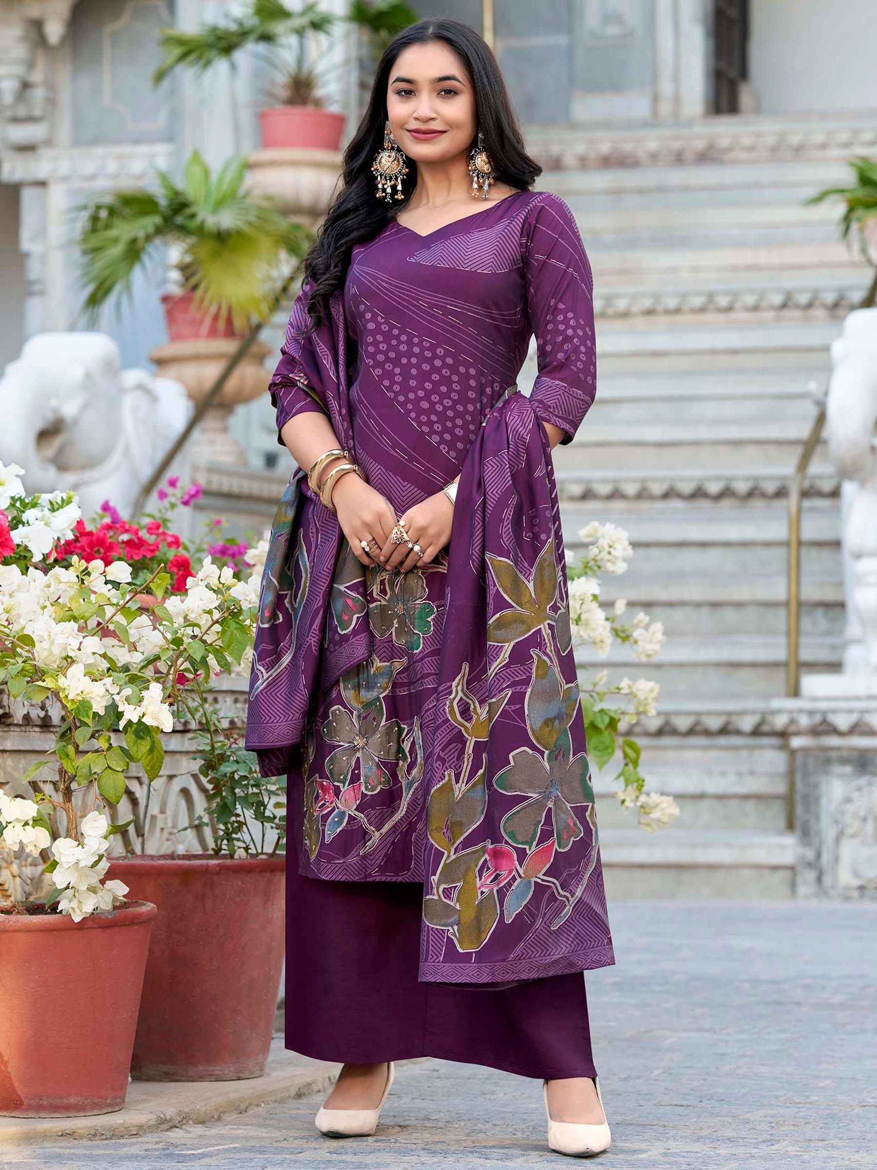 Woman in purple designer salwar kameez with floral dupatta, traditional jewelry, outdoor setting