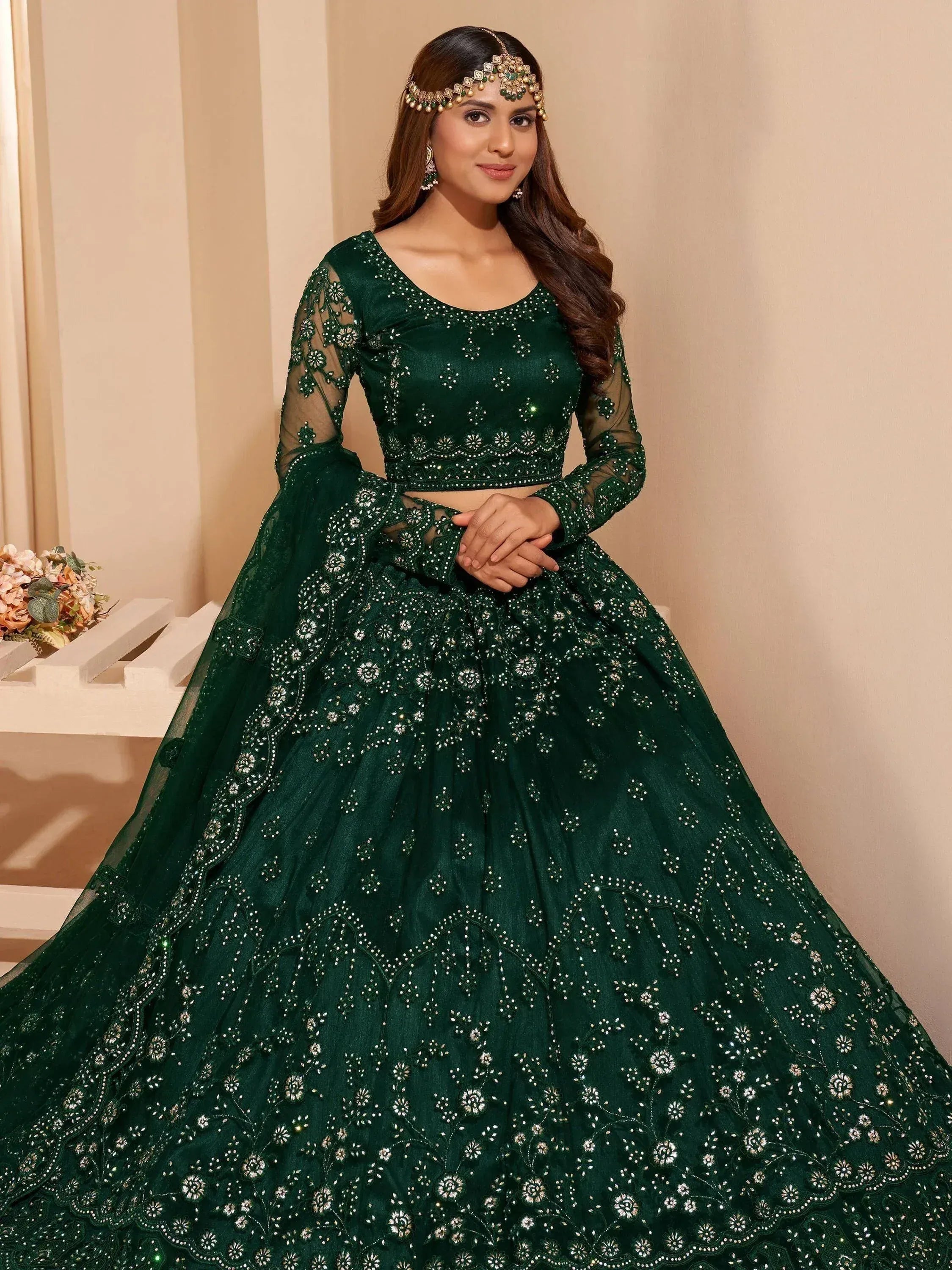 Emerald green designer lehenga choli with intricate floral embroidery and sheer sleeves, perfect for weddings.