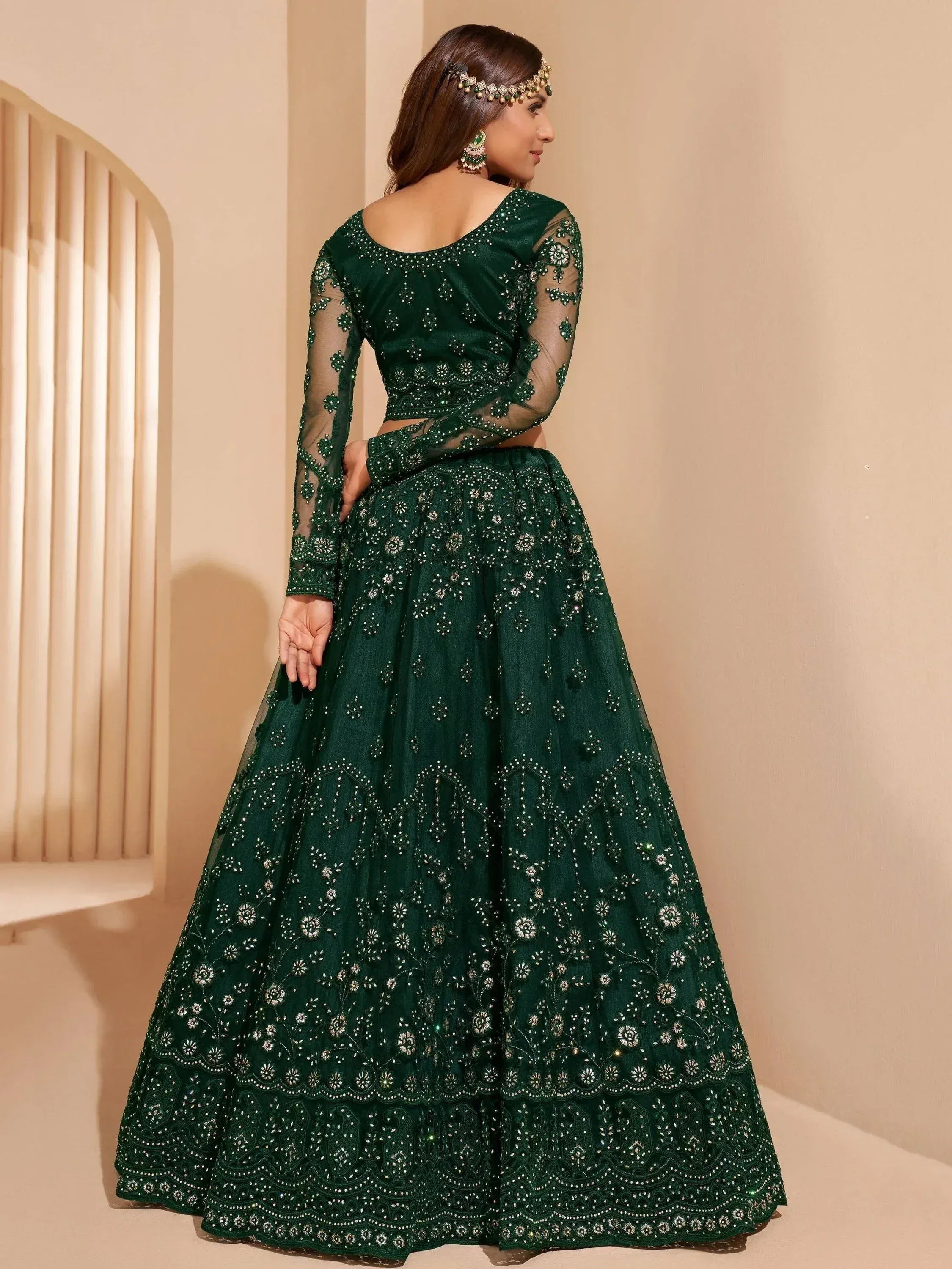 Emerald green designer lehenga choli with intricate embroidery and sheer sleeves, perfect for Indian ethnic wear.