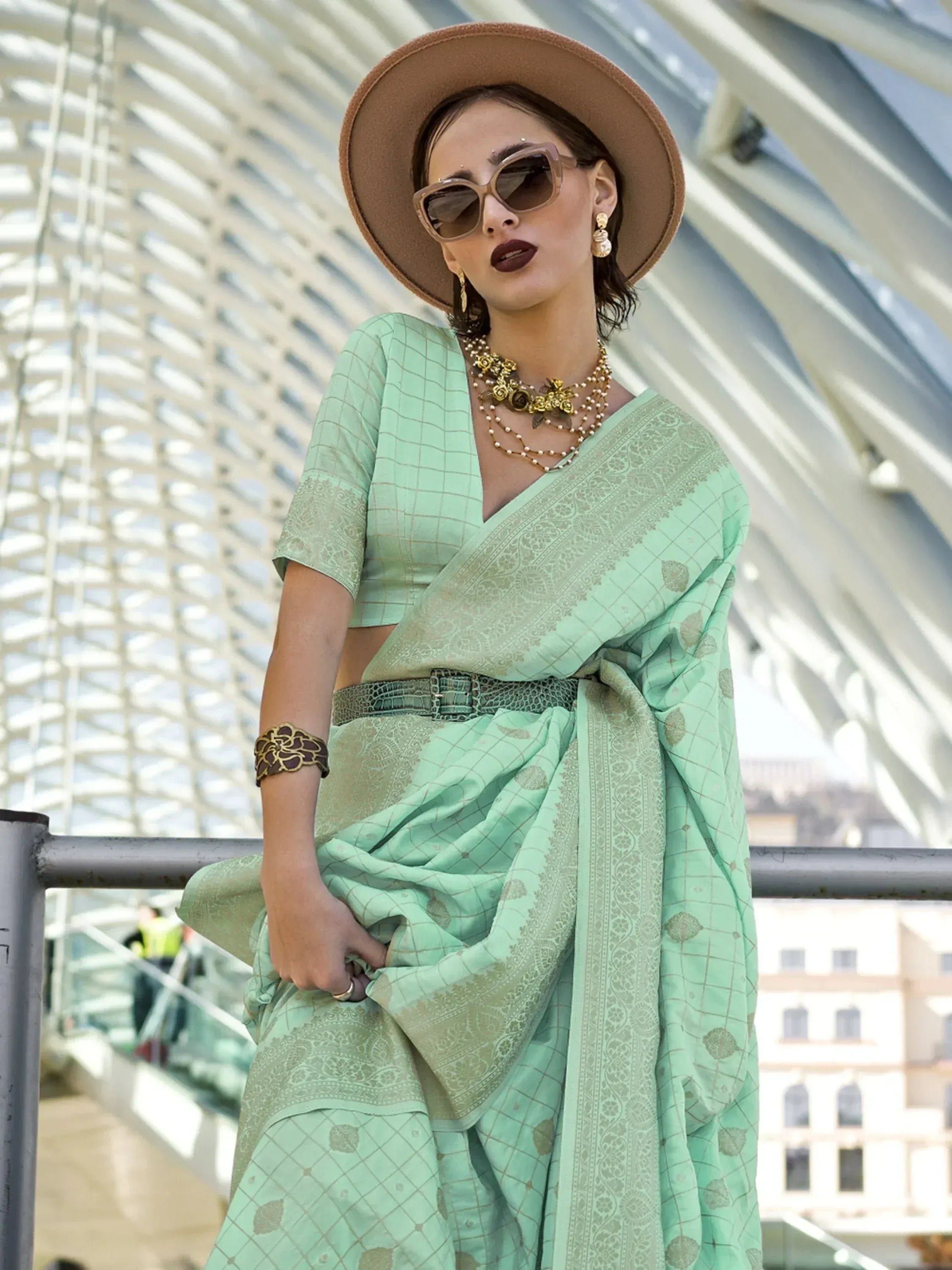 Mint green printed saree with blouse, styled with hat and gold jewelry for ethnic wear