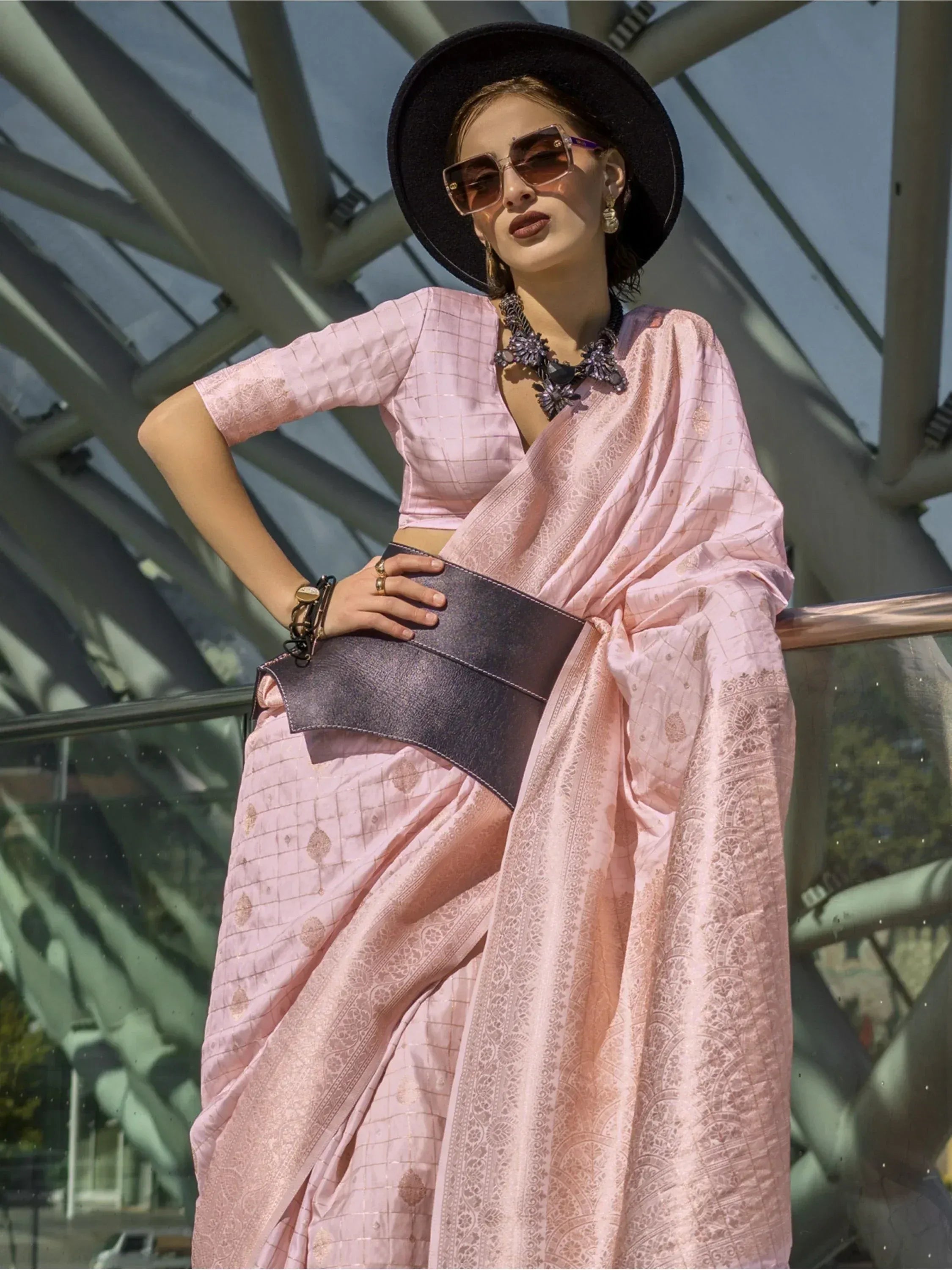 Pink printed saree with matching blouse, styled with black hat and statement jewelry for ethnic wear