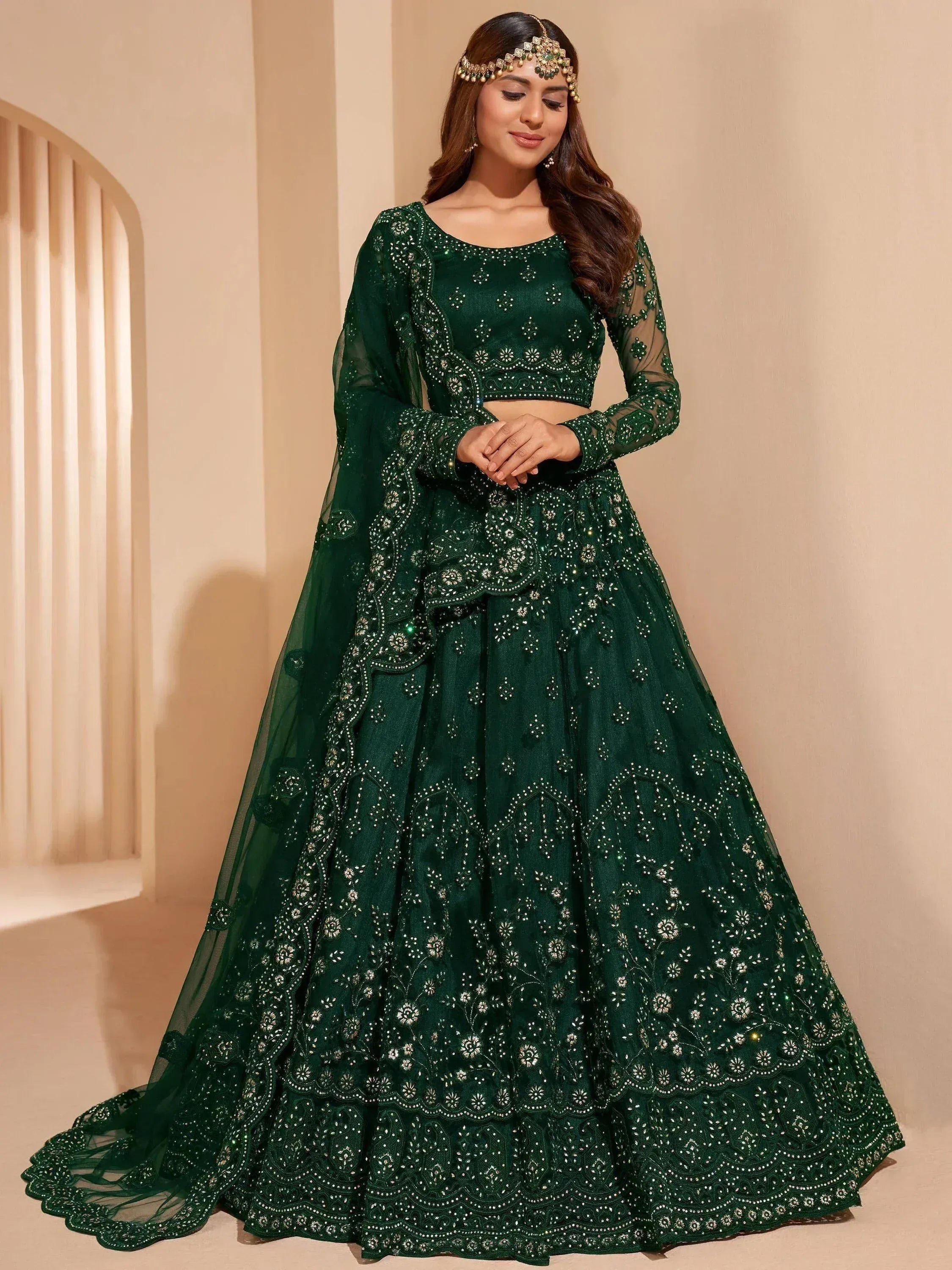 Emerald green designer lehenga choli with intricate embroidery and sheer sleeves, perfect for weddings and festive occasions.