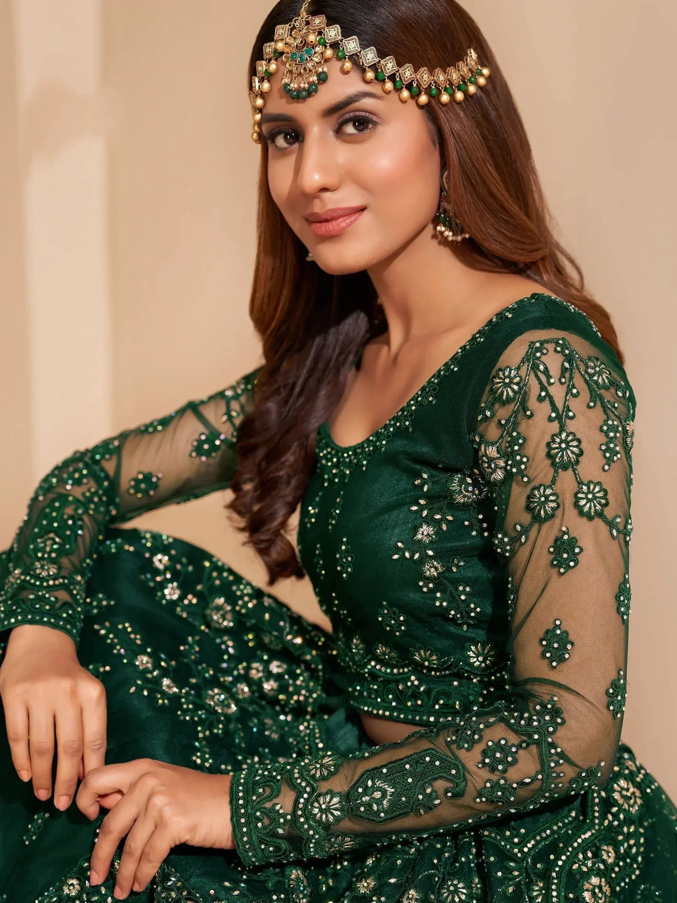 Emerald green embroidered lehenga choli with sheer sleeves and traditional maang tikka, perfect for Indian ethnic wear.