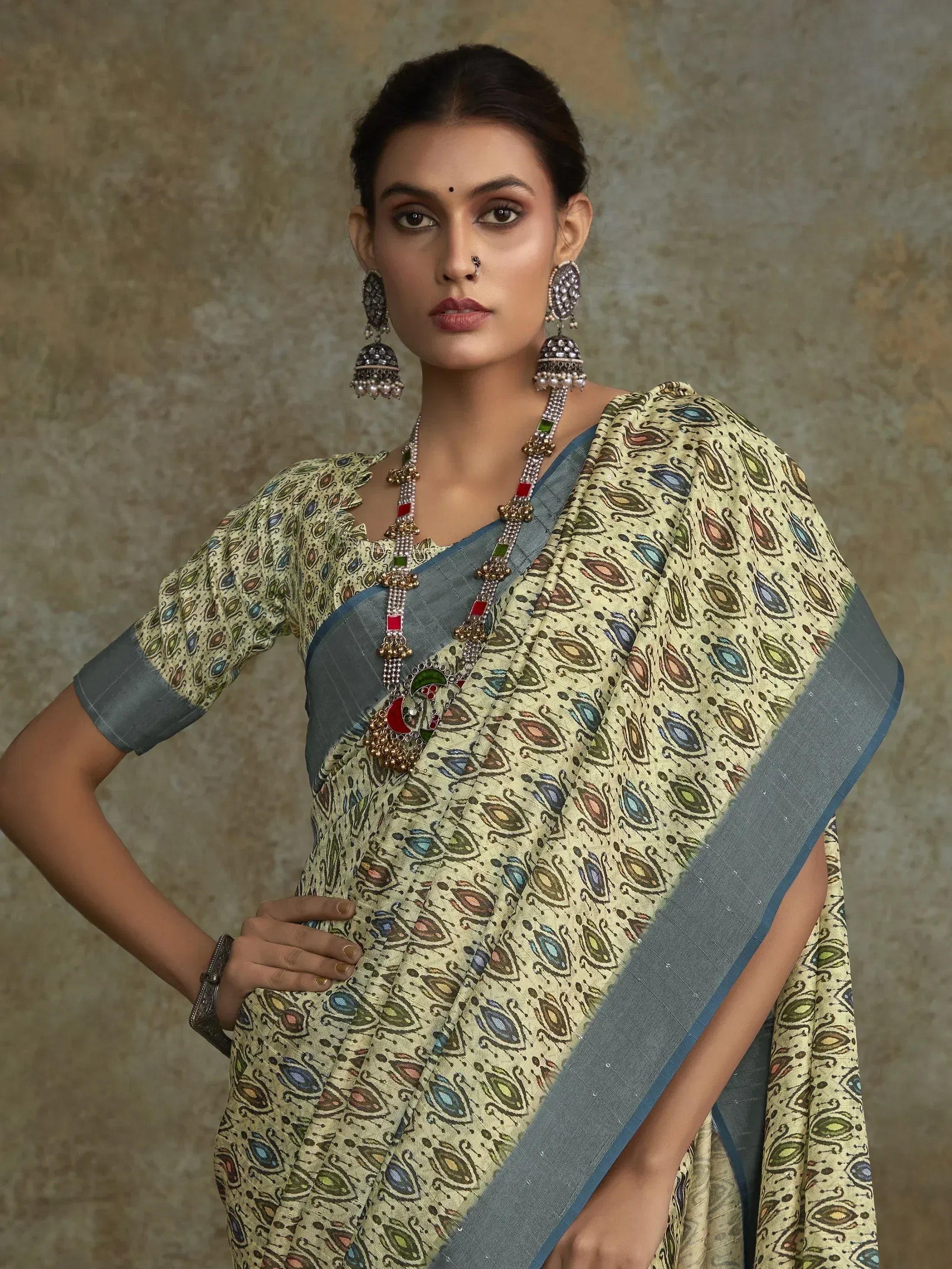 Woman in printed ethnic saree with blue border, traditional jewelry, and nose ring