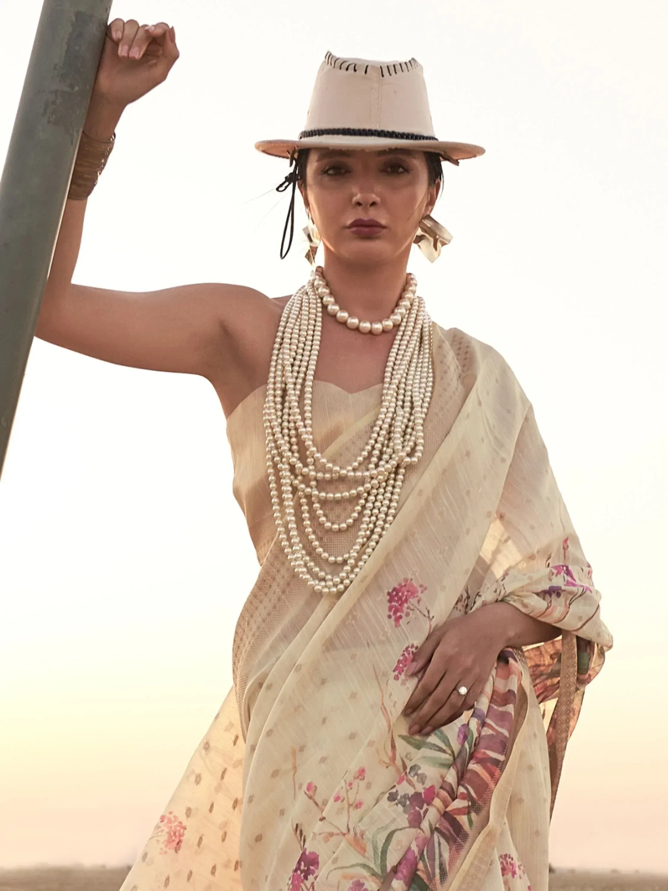 Woman in floral saree with pearl necklace and hat, ethnic Indian wear