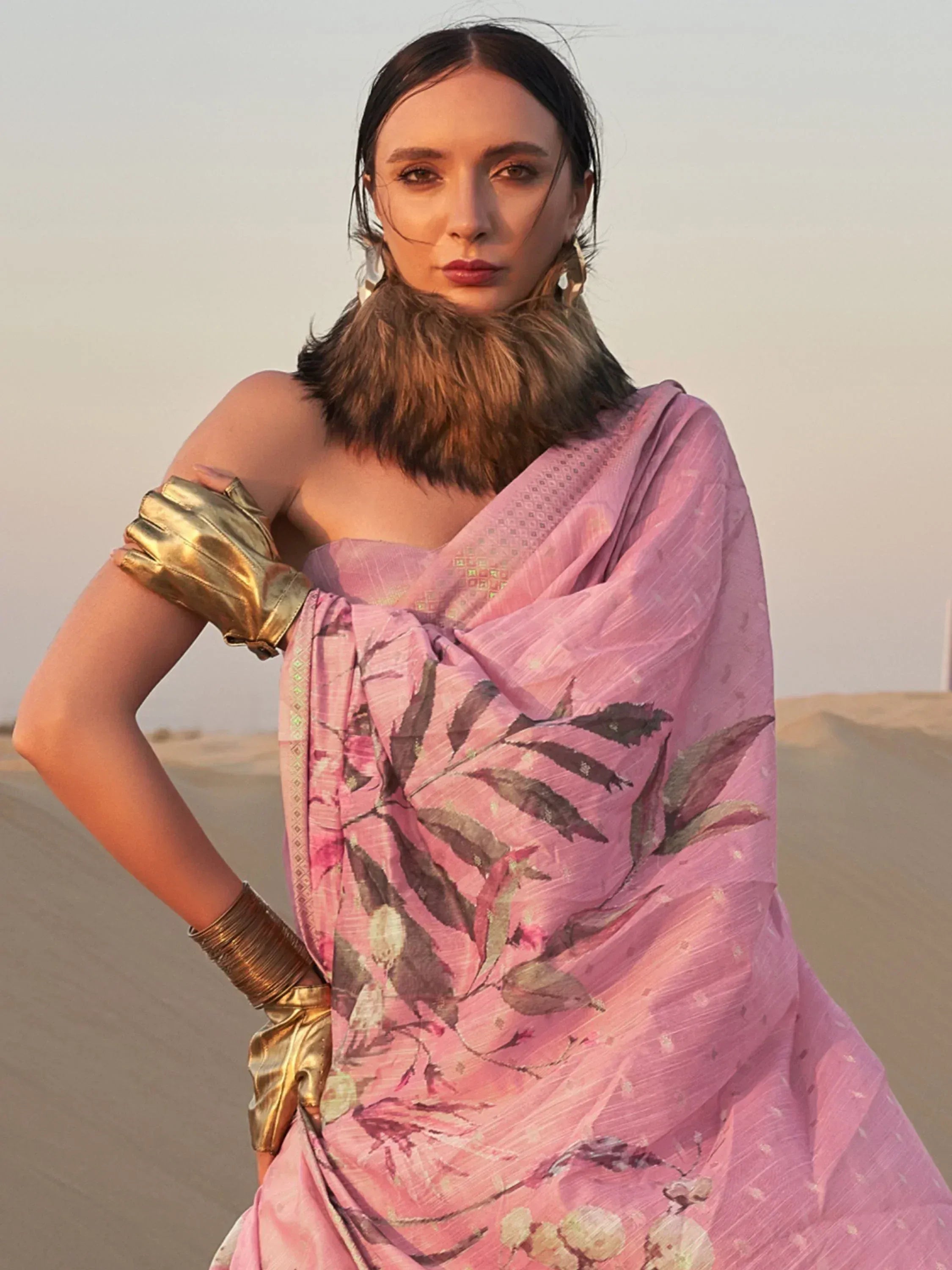 Woman in pink floral ethnic gown with gold gloves, desert backdrop, Indian fashion