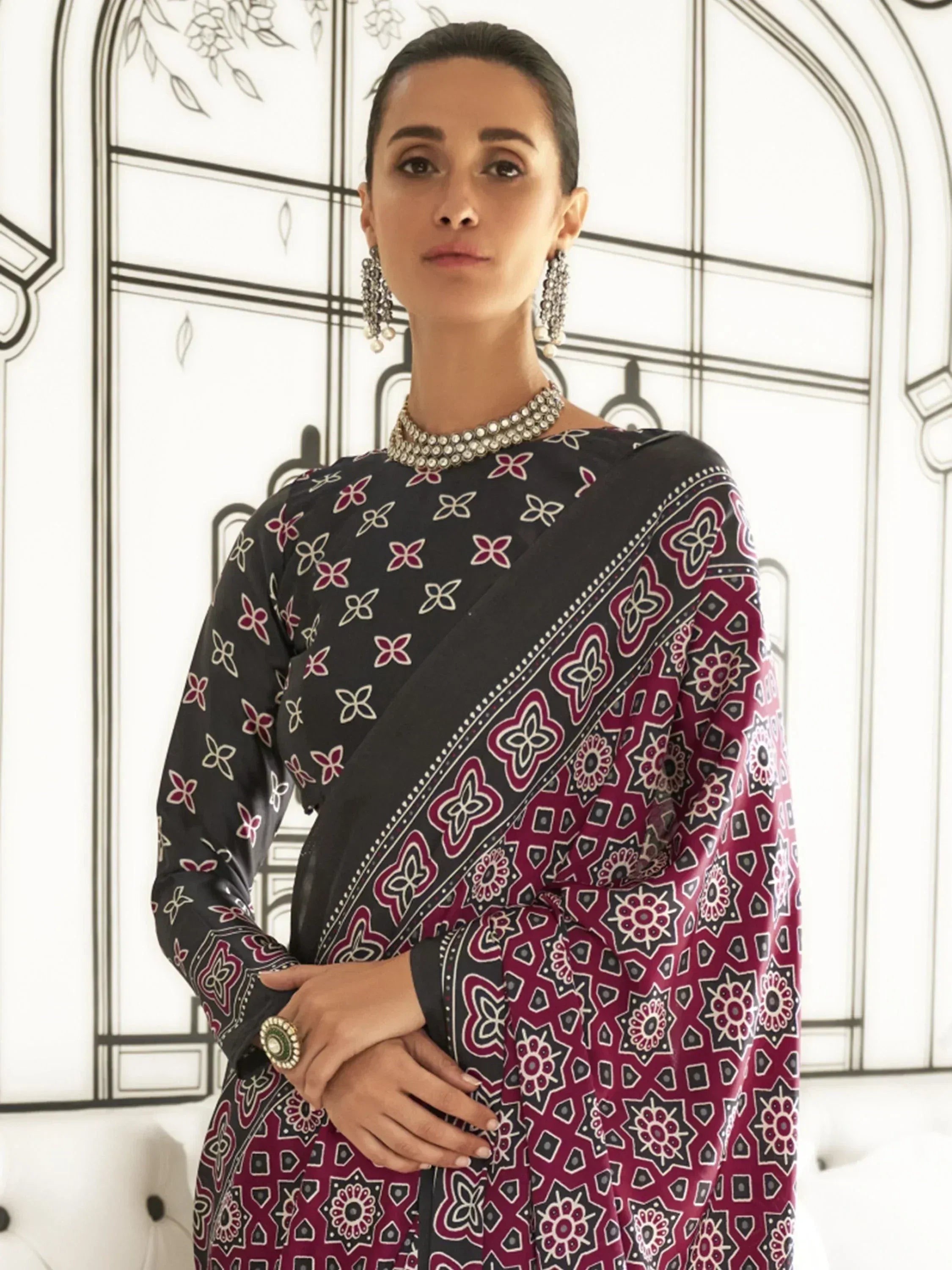 Woman in black and maroon printed saree with floral motifs, styled with statement jewelry for ethnic wear
