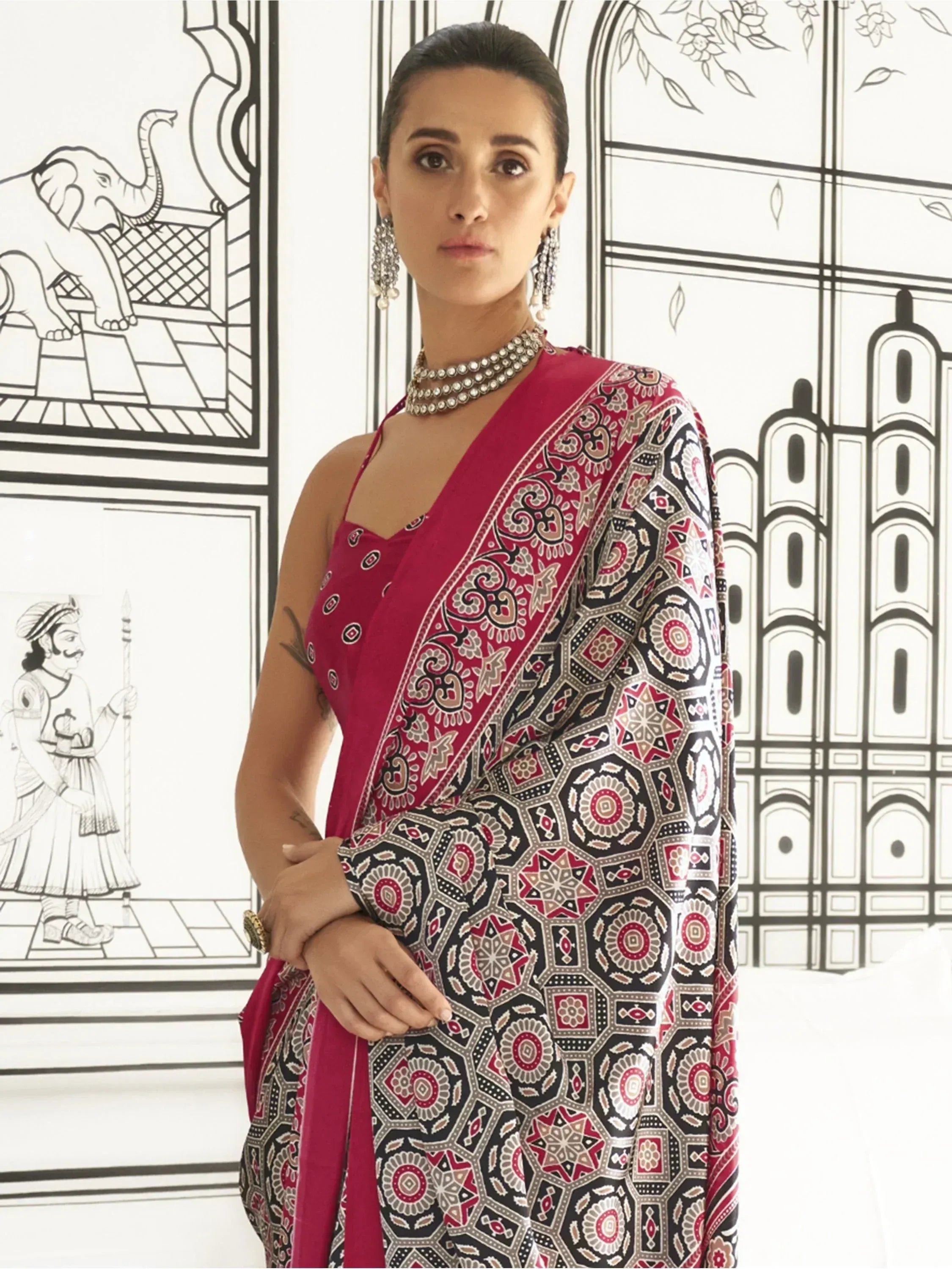 Woman in red and black printed saree with ethnic jewelry, styled for Indian occasions