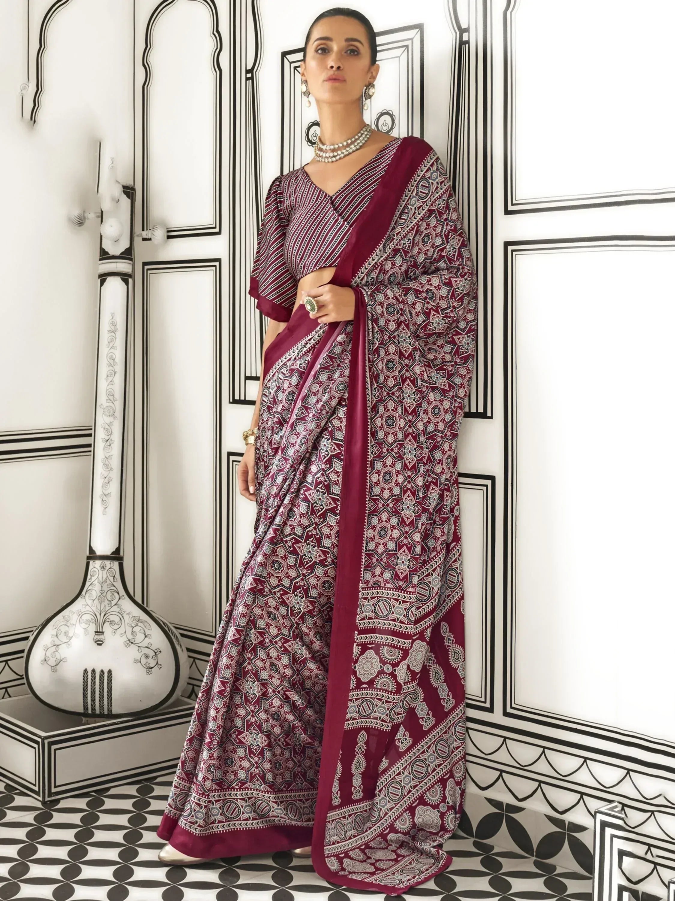 Maroon printed saree with geometric patterns, styled with pearl jewelry and ethnic accessories