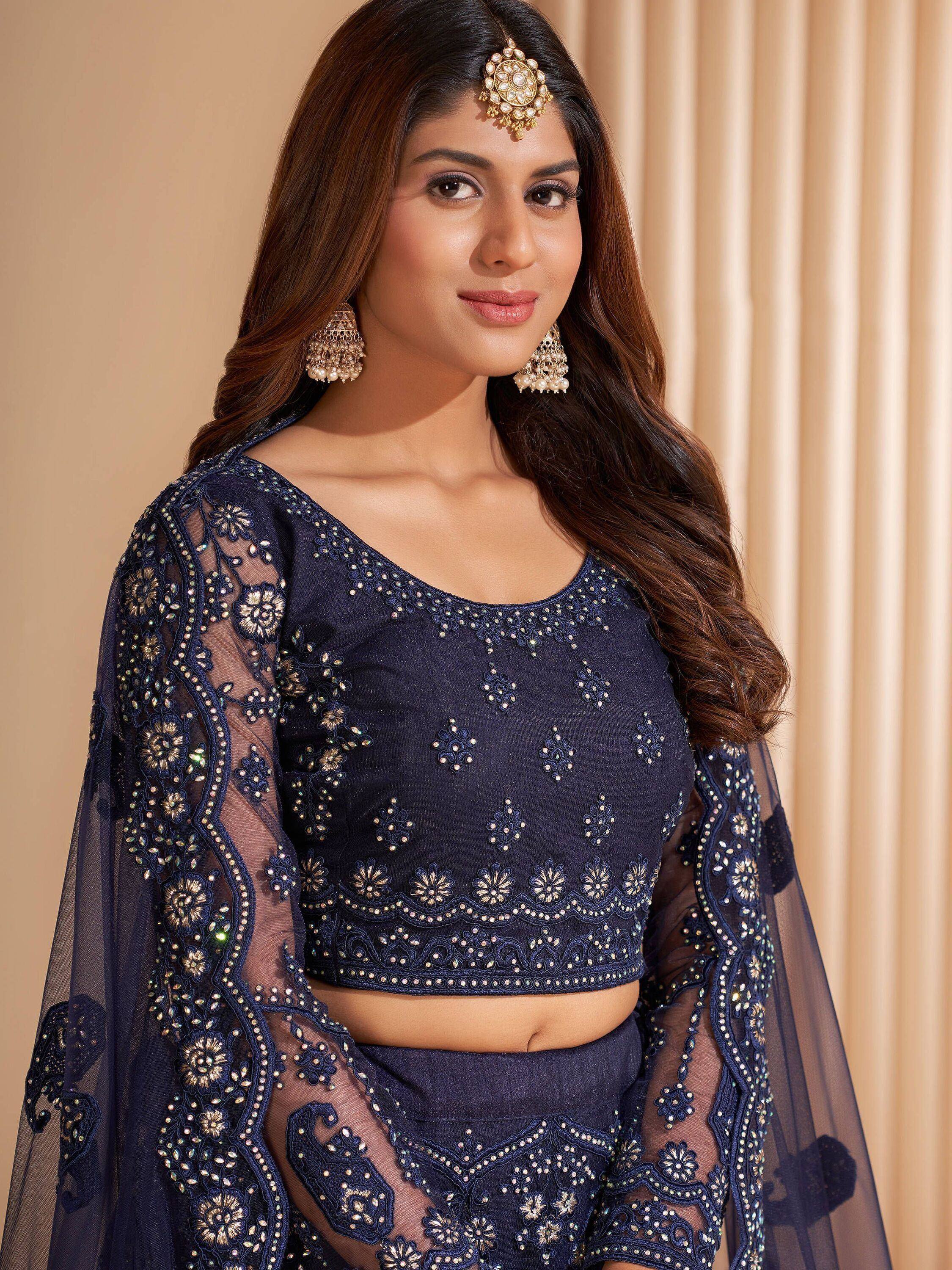 Navy blue embroidered lehenga choli with sheer sleeves and gold jewelry, perfect for Indian ethnic wear.