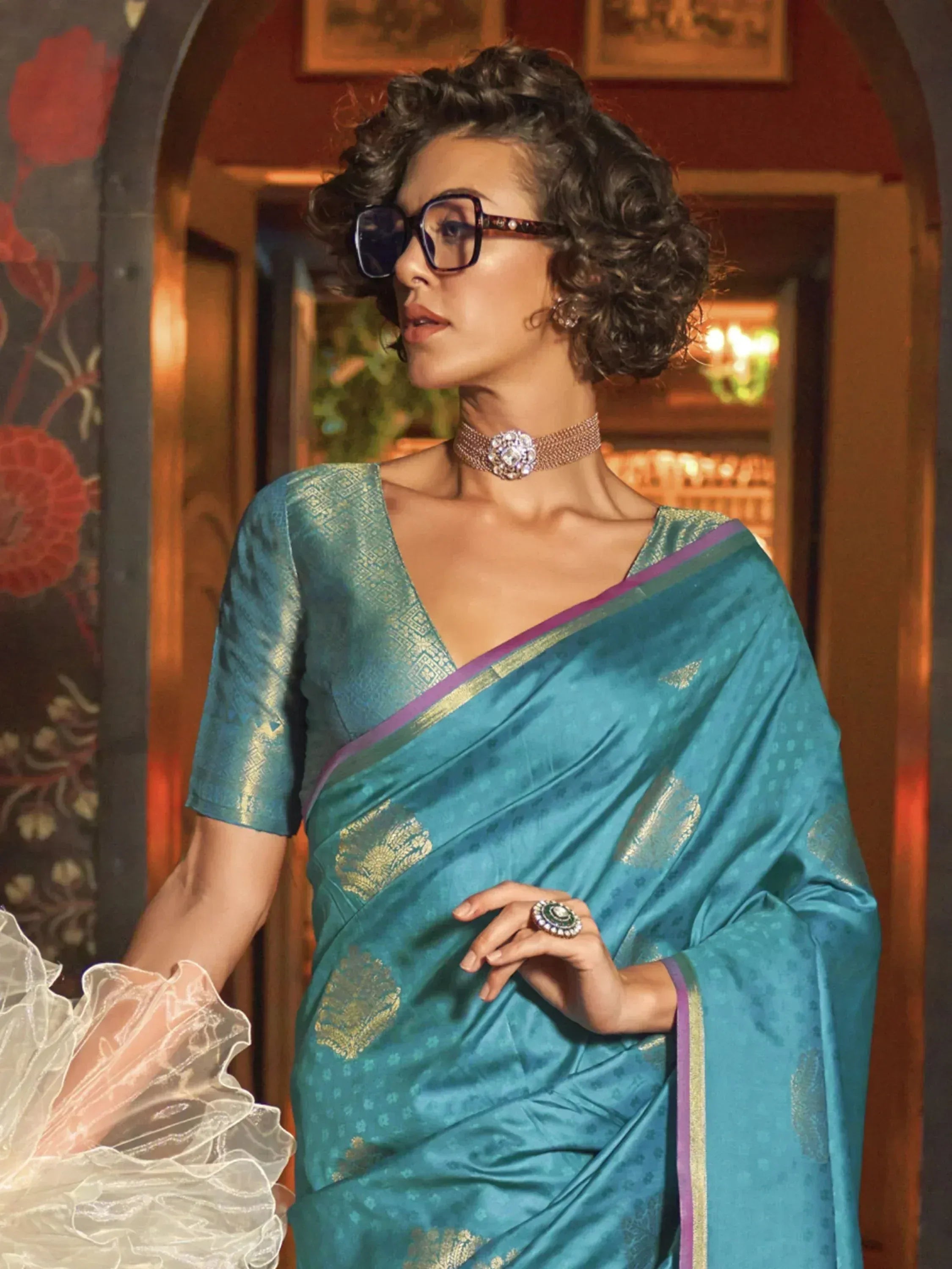 Teal silk saree with gold motifs and purple border, styled with statement jewelry for ethnic wear
