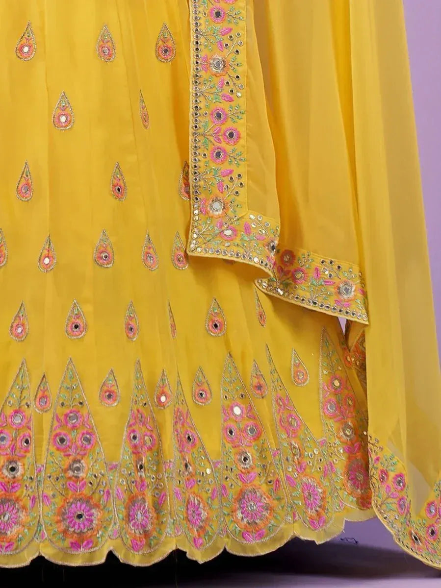 Yellow ethnic gown with floral embroidery and mirror work, perfect for Indian occasions