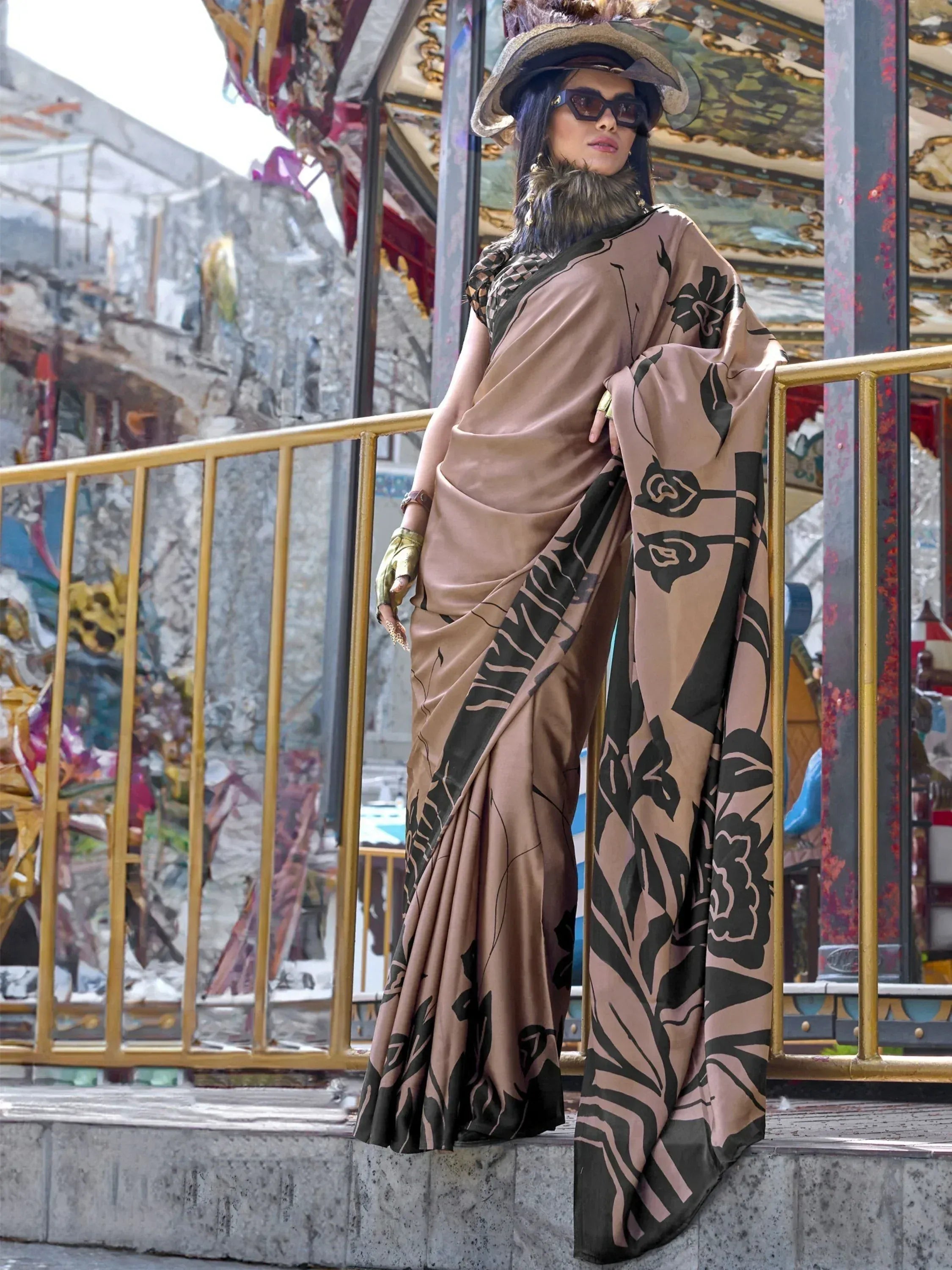 Elegant brown saree with black floral print, styled with a hat and gloves for a chic ethnic look.