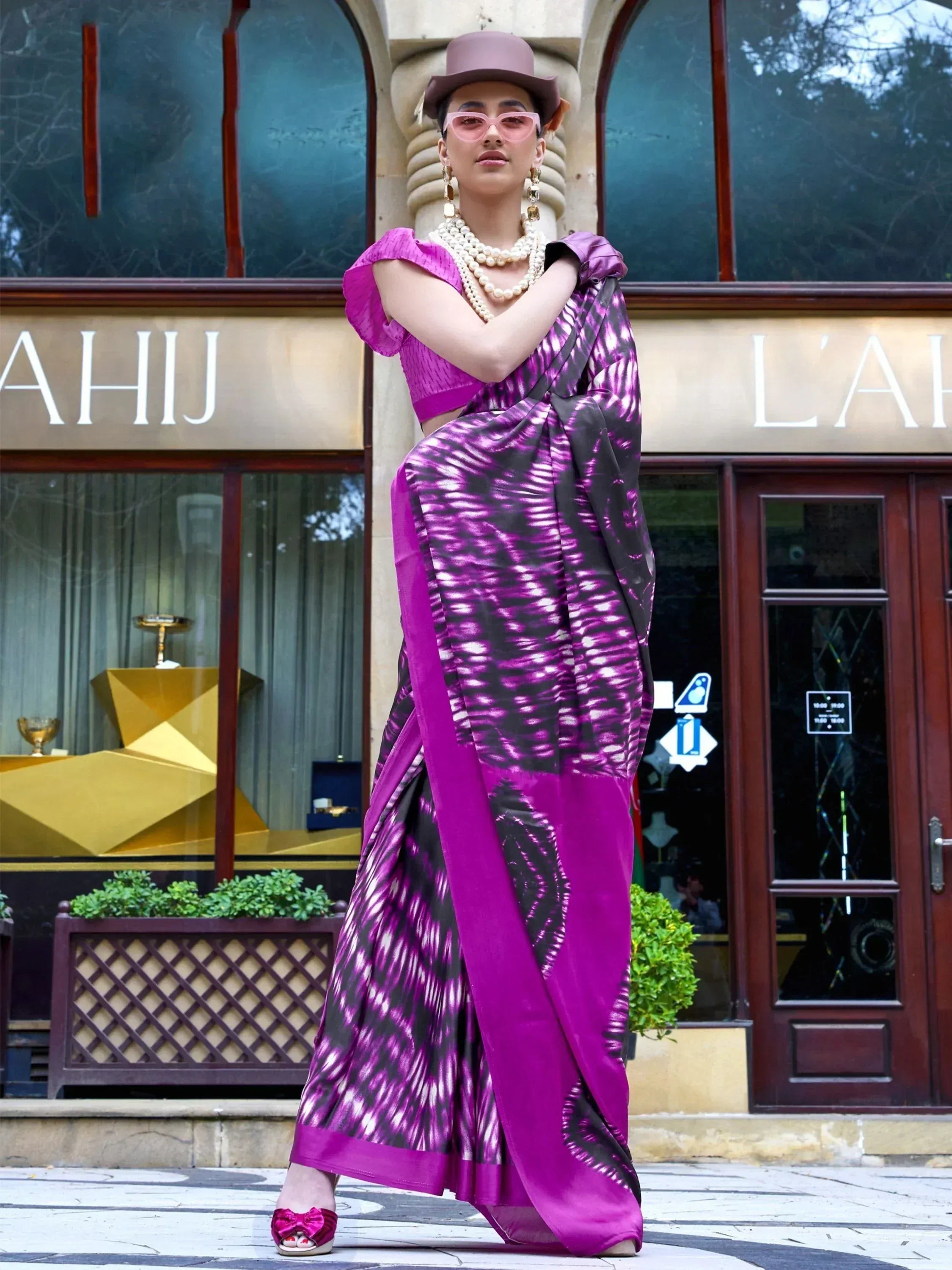 Vibrant purple tie-dye saree with matching blouse, styled with hat and pearls for ethnic fashion