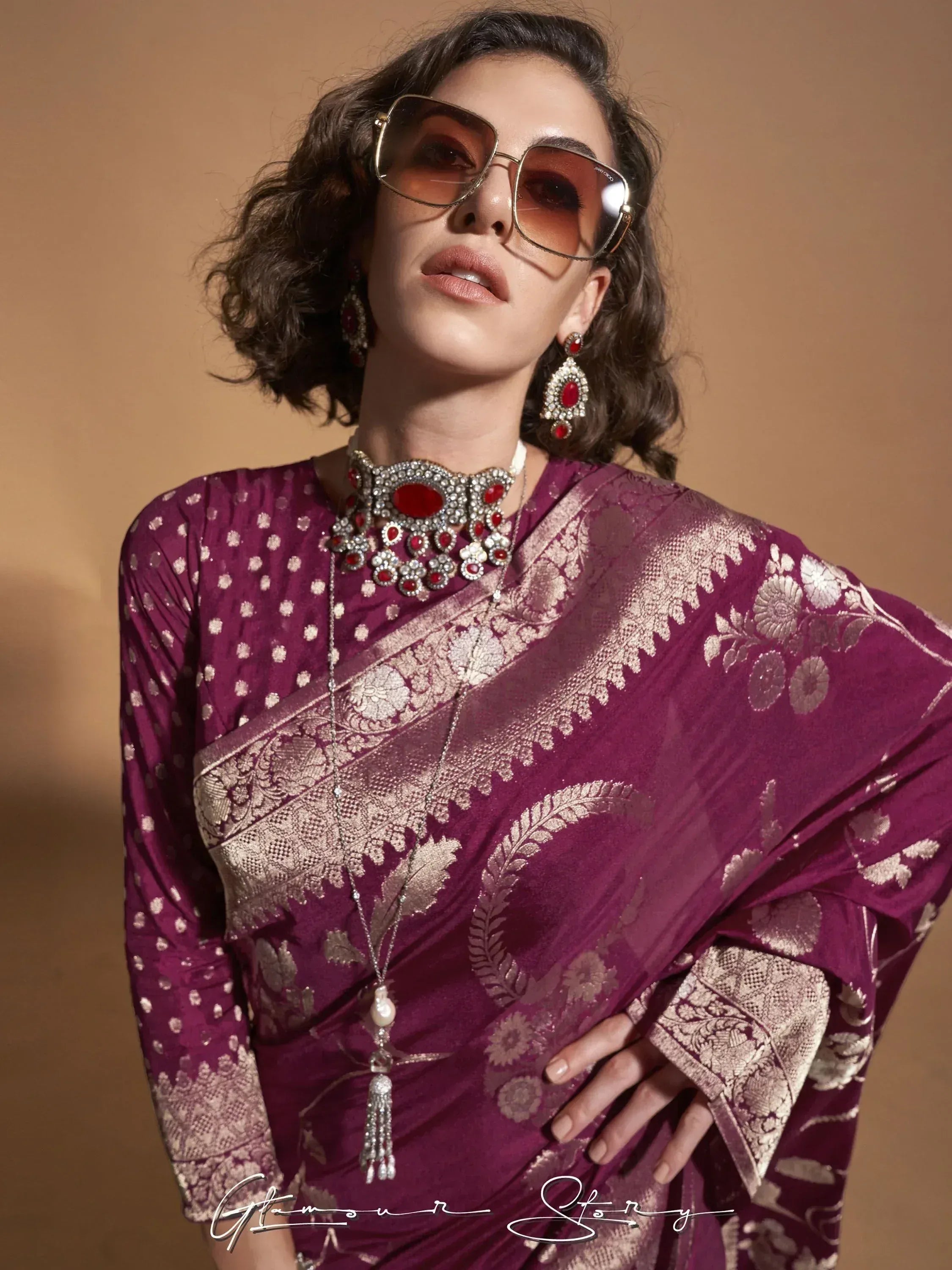 Elegant purple saree with gold floral embroidery, paired with statement red jewelry and sunglasses