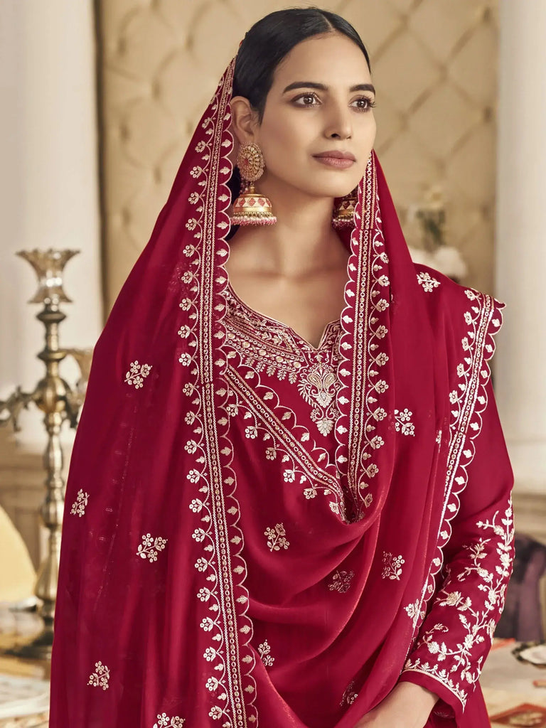 Woman wearing a red embroidered traditional outfit indoors.