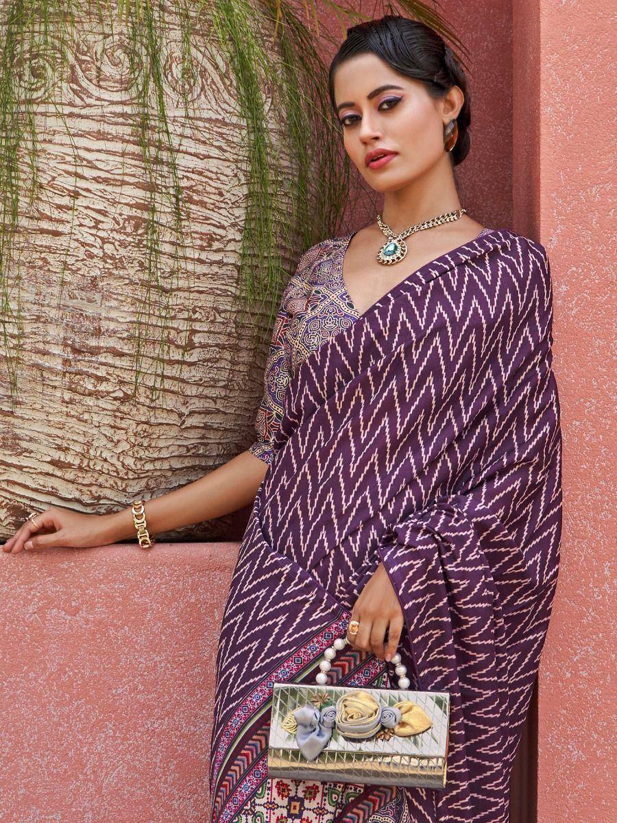 Purple ikat saree with geometric print, ethnic jewelry, and floral clutch for Indian festive wear
