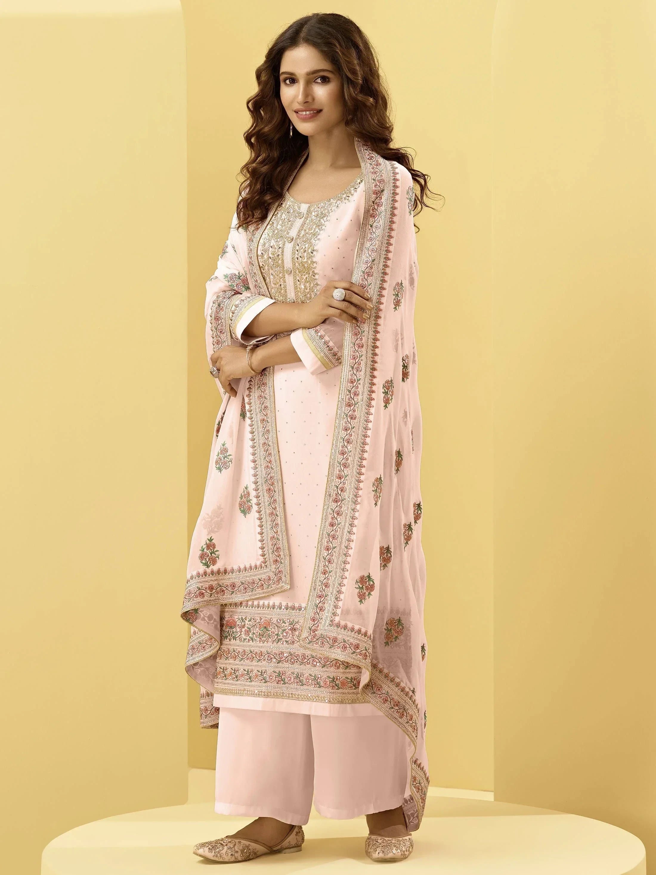 Woman in pastel pink embroidered salwar kameez with matching dupatta and jutti shoes