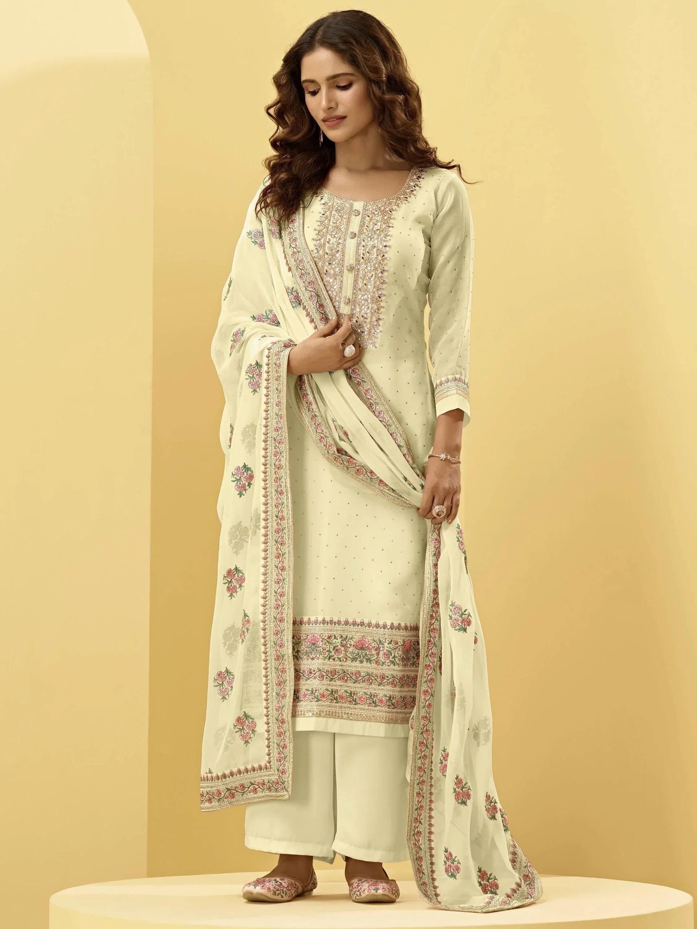 Woman wearing cream embroidered salwar kameez with floral dupatta and traditional juttis