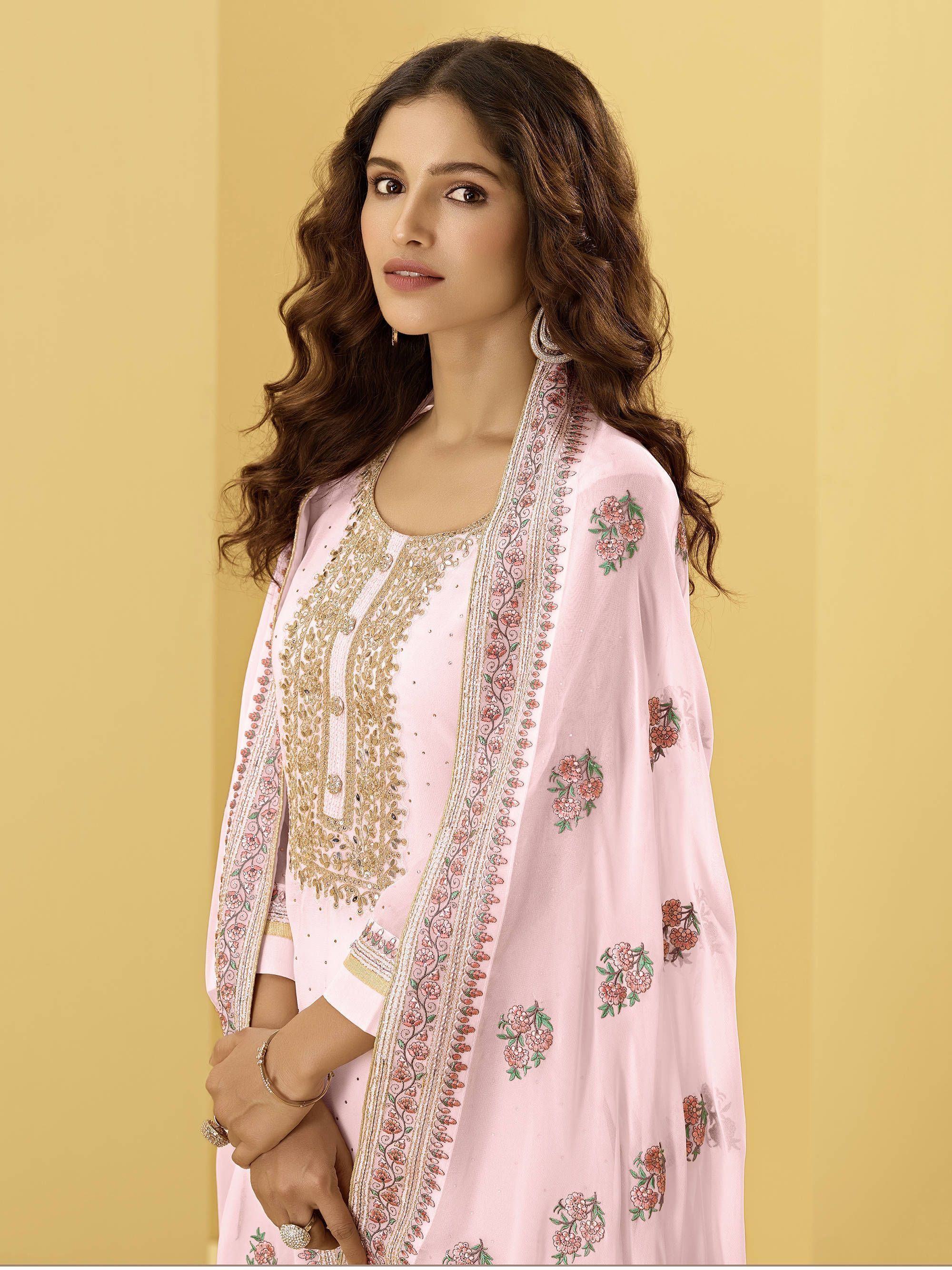 Woman in light pink embroidered salwar kameez with floral dupatta, traditional Indian ethnic wear.