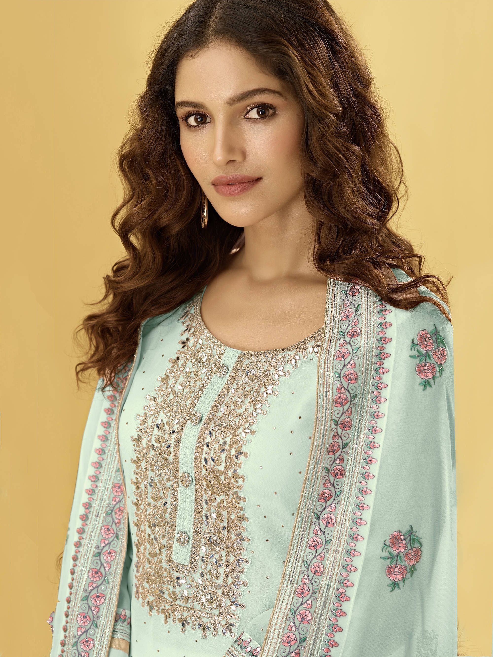 Woman wearing light blue embroidered salwar kameez with floral dupatta on yellow background