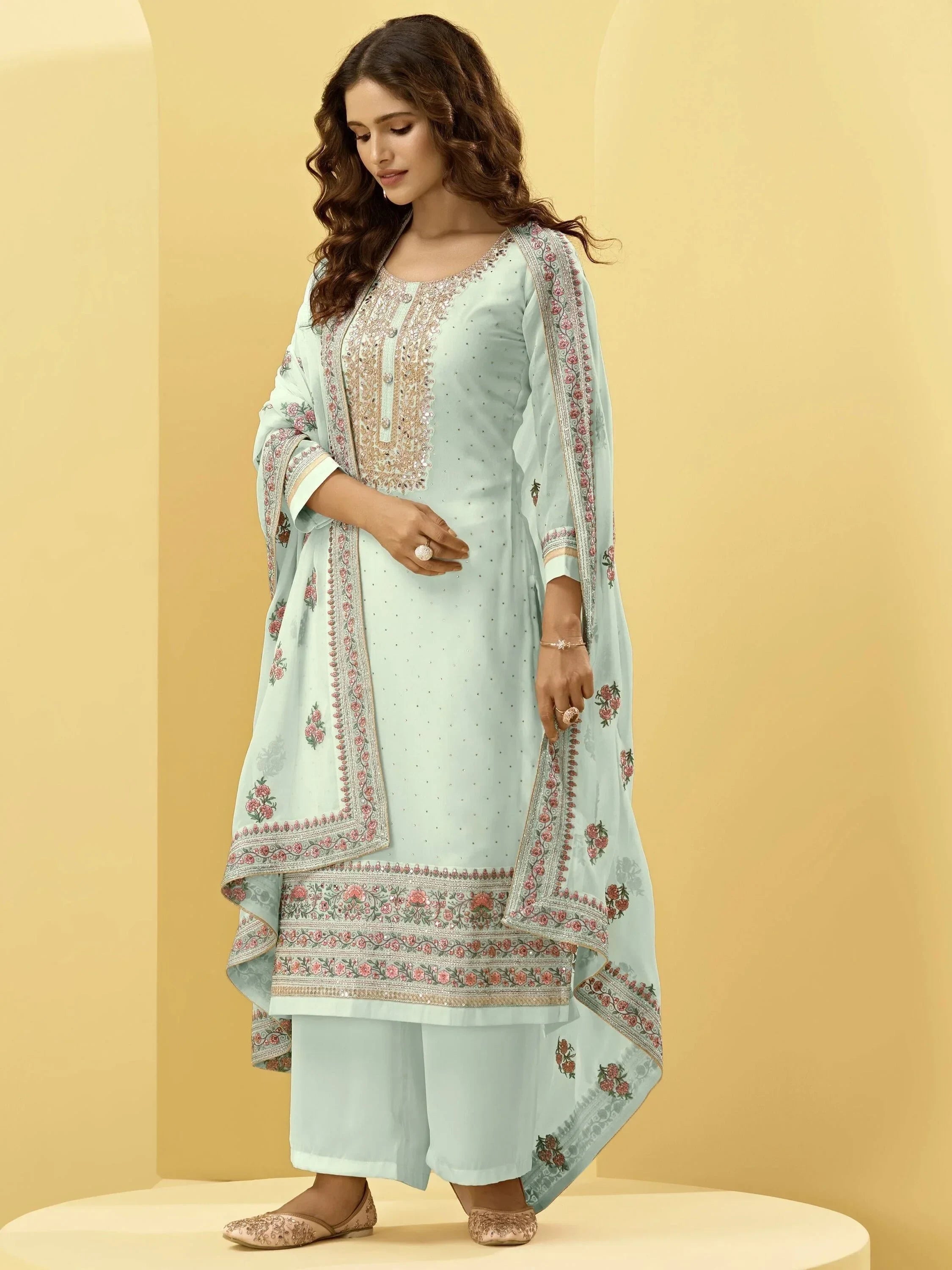 Woman wearing light blue embroidered salwar kameez with floral dupatta and juttis