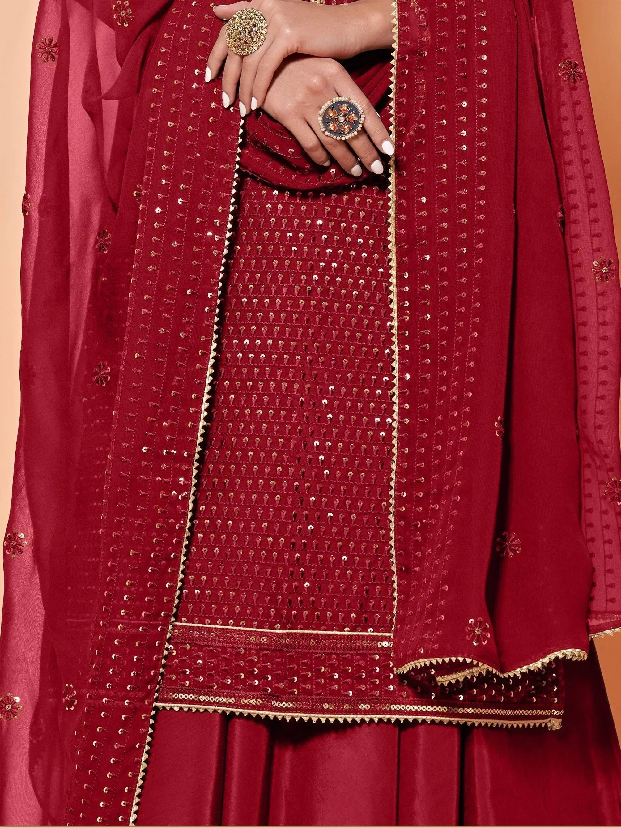 Elegant maroon ethnic wear with intricate gold embroidery and embellishments, perfect for festive occasions.