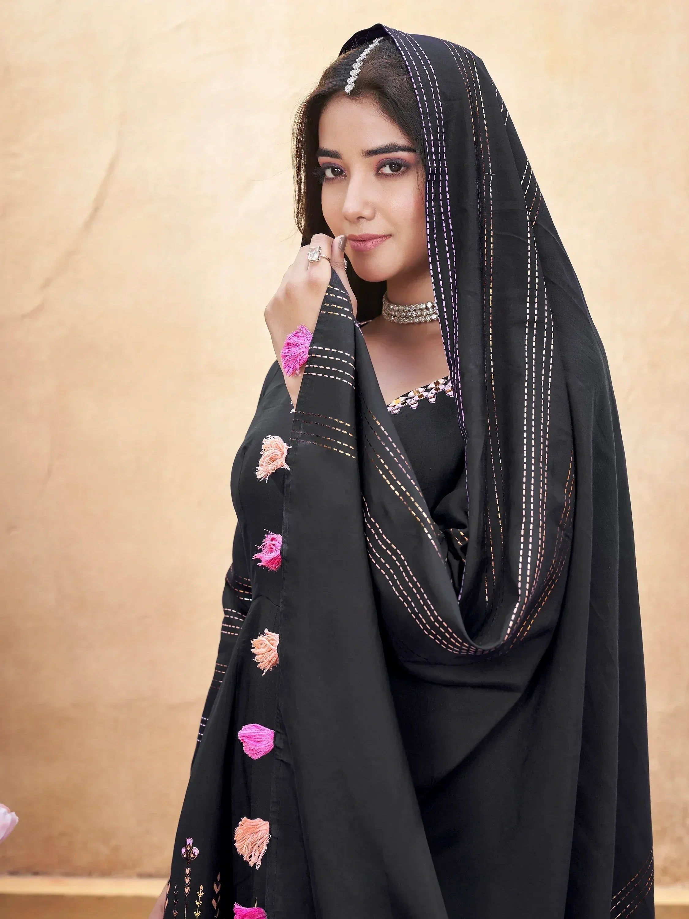 Black ethnic salwar kameez with pink tassels and embroidery, styled with dupatta and jewelry