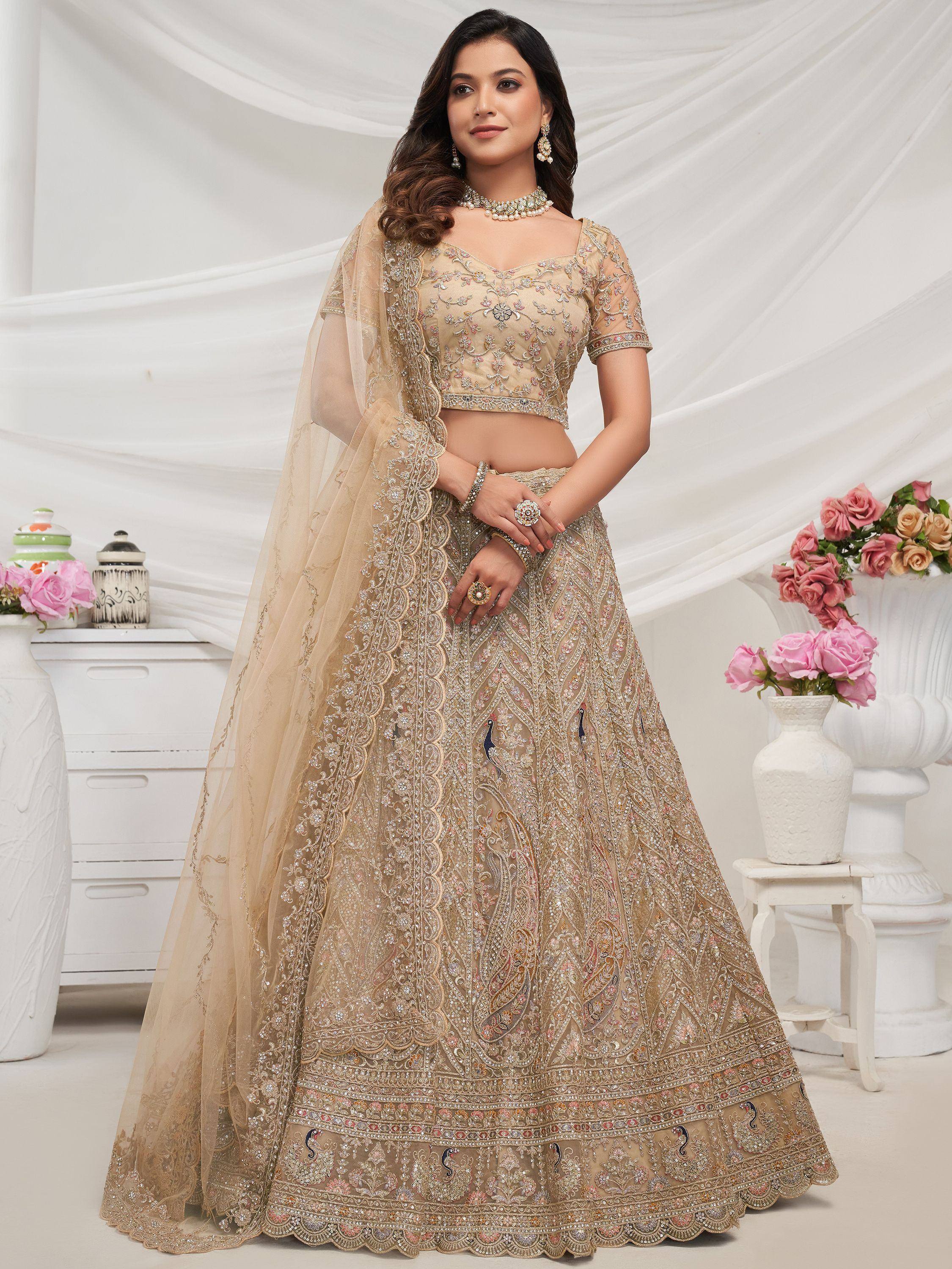 Elegant beige lehenga choli with intricate embroidery, peacock motifs, and sheer dupatta for Indian weddings