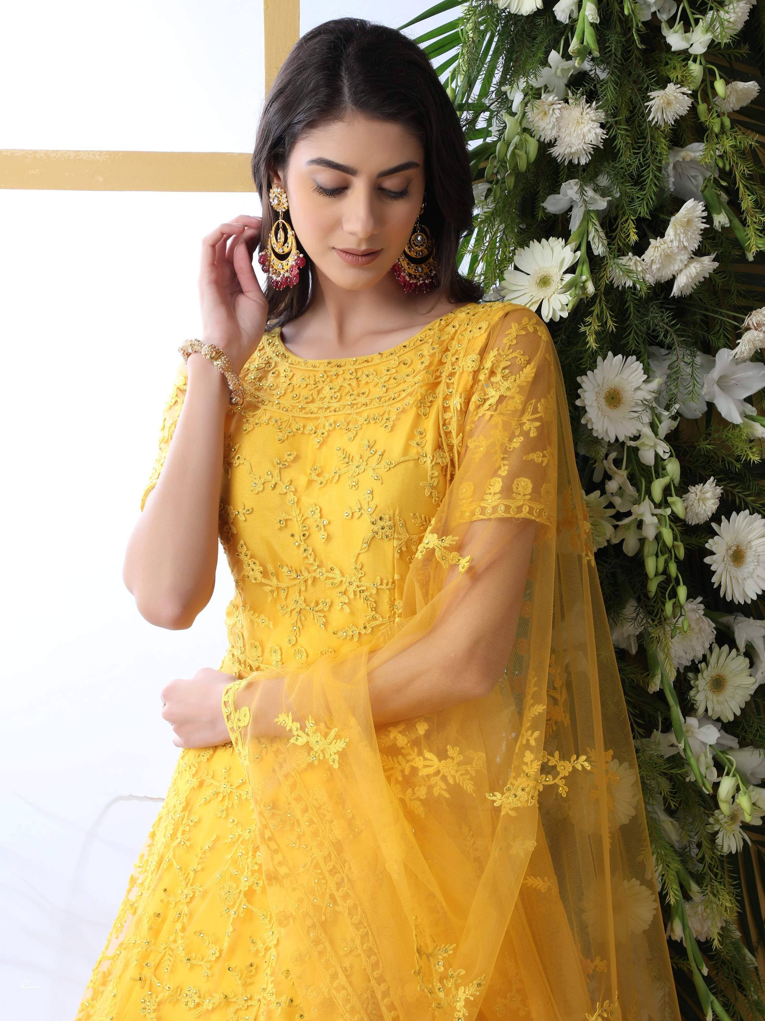 Yellow embroidered ethnic gown with sheer sleeves, paired with statement earrings, perfect for Indian celebrations.