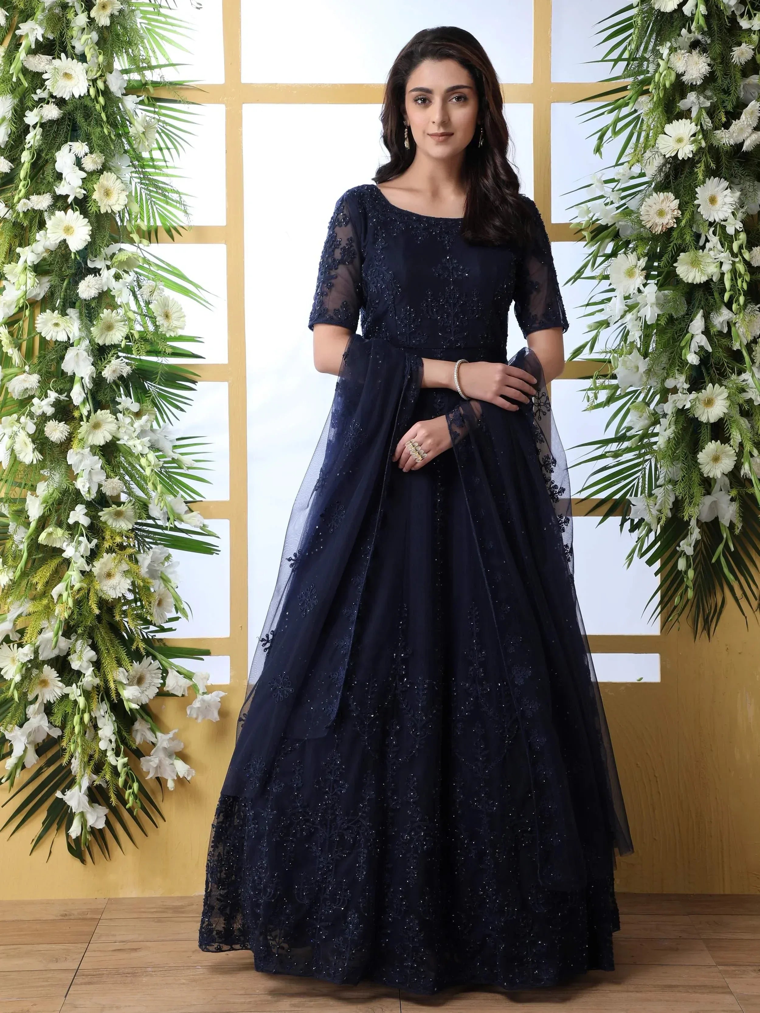 Navy blue embroidered ethnic gown with sheer sleeves and floral backdrop