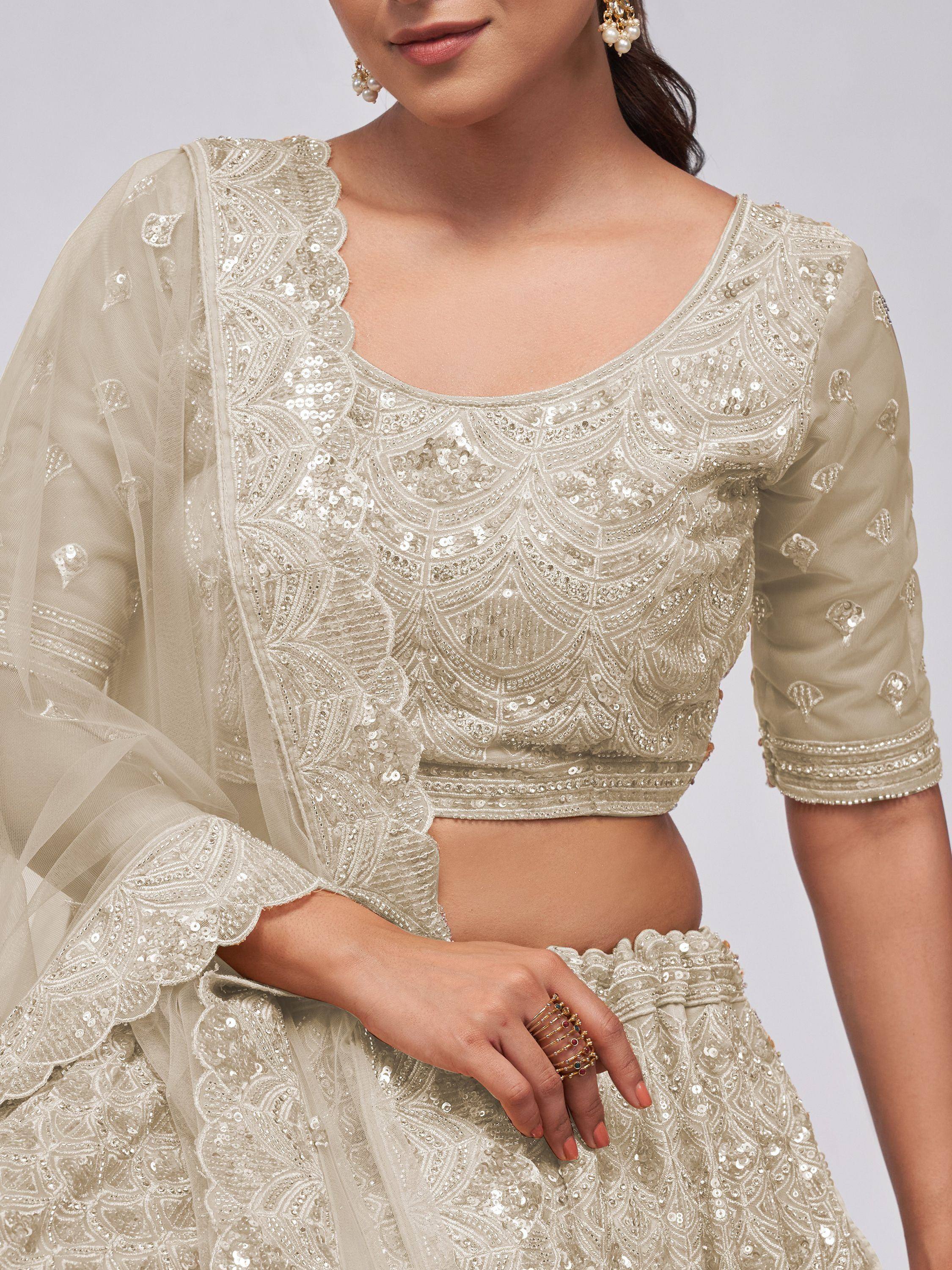 Elegant ivory lehenga choli with intricate sequin embroidery and sheer dupatta, perfect for Indian weddings or festive occasions.